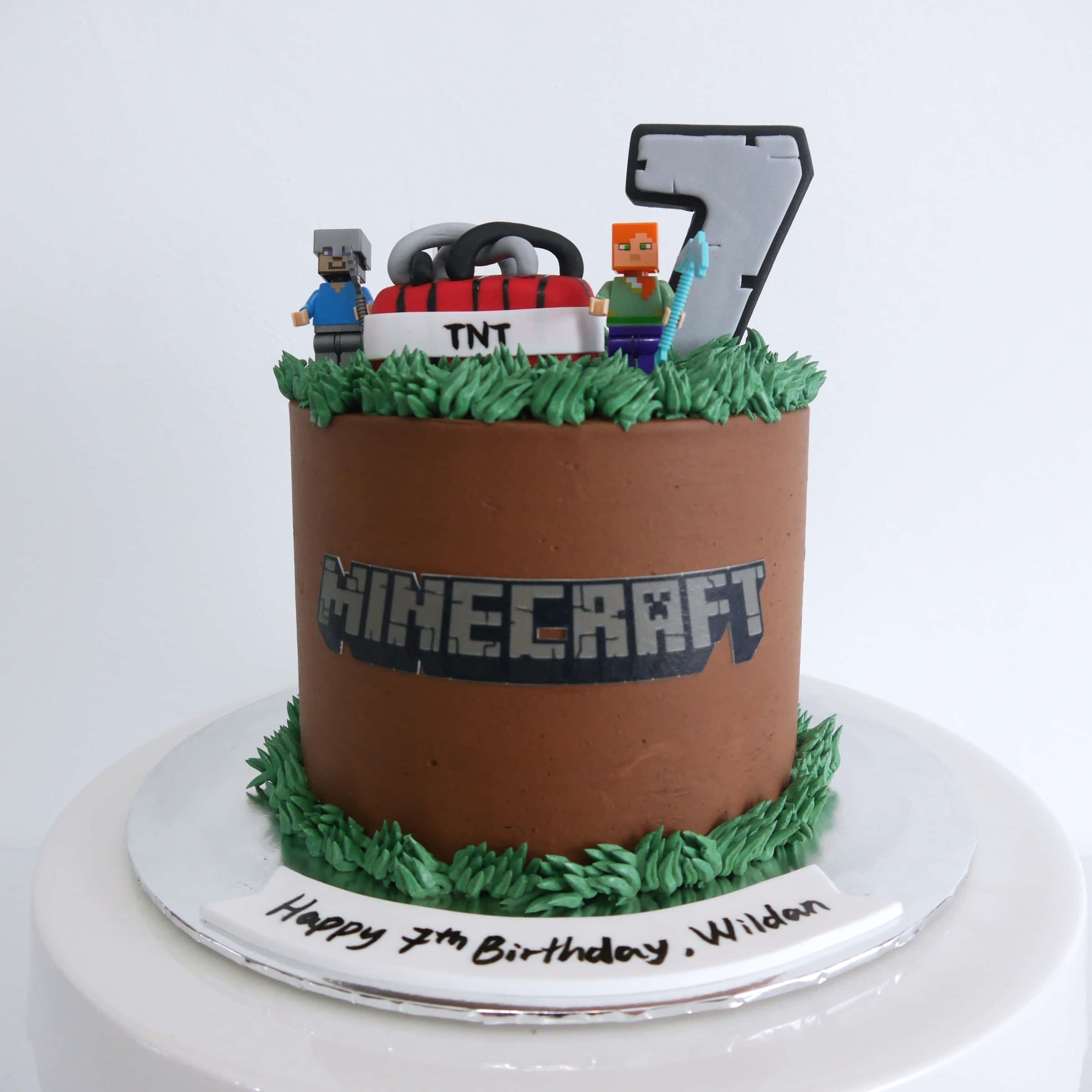 Minecraft Cakes 桌布 壁紙 — 一個以Minecraft為主題的生日蛋糕，上面有像素化角色和TNT裝飾，蛋糕體為棕色泥土紋理。