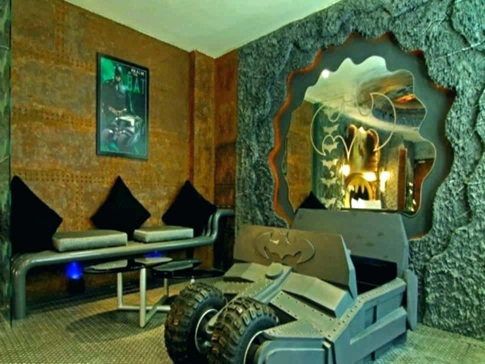 Batcave 桌布 壁紙 — 一個以蝙蝠俠為主題的房間，配備蝙蝠車造型床、粗獷的石牆，以及在溫暖燈光下的裱框海報。