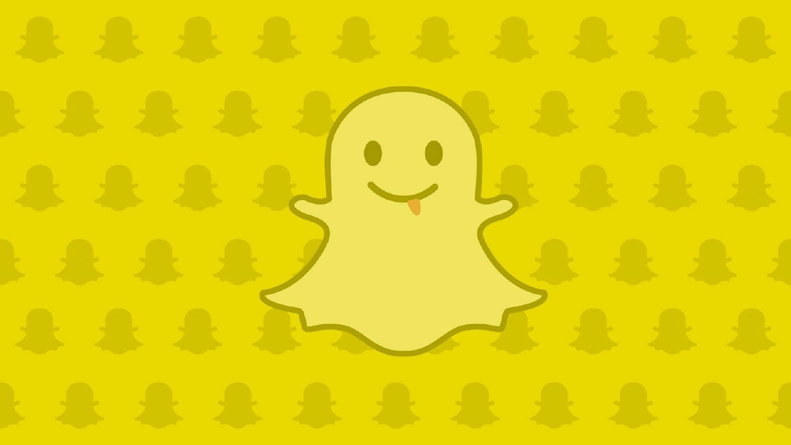 Snapchat 桌布 壁紙 — 一個伸出舌頭的開心黃色鬼魂漂浮在重複的鬼魂圖案上，背景為亮黃色。