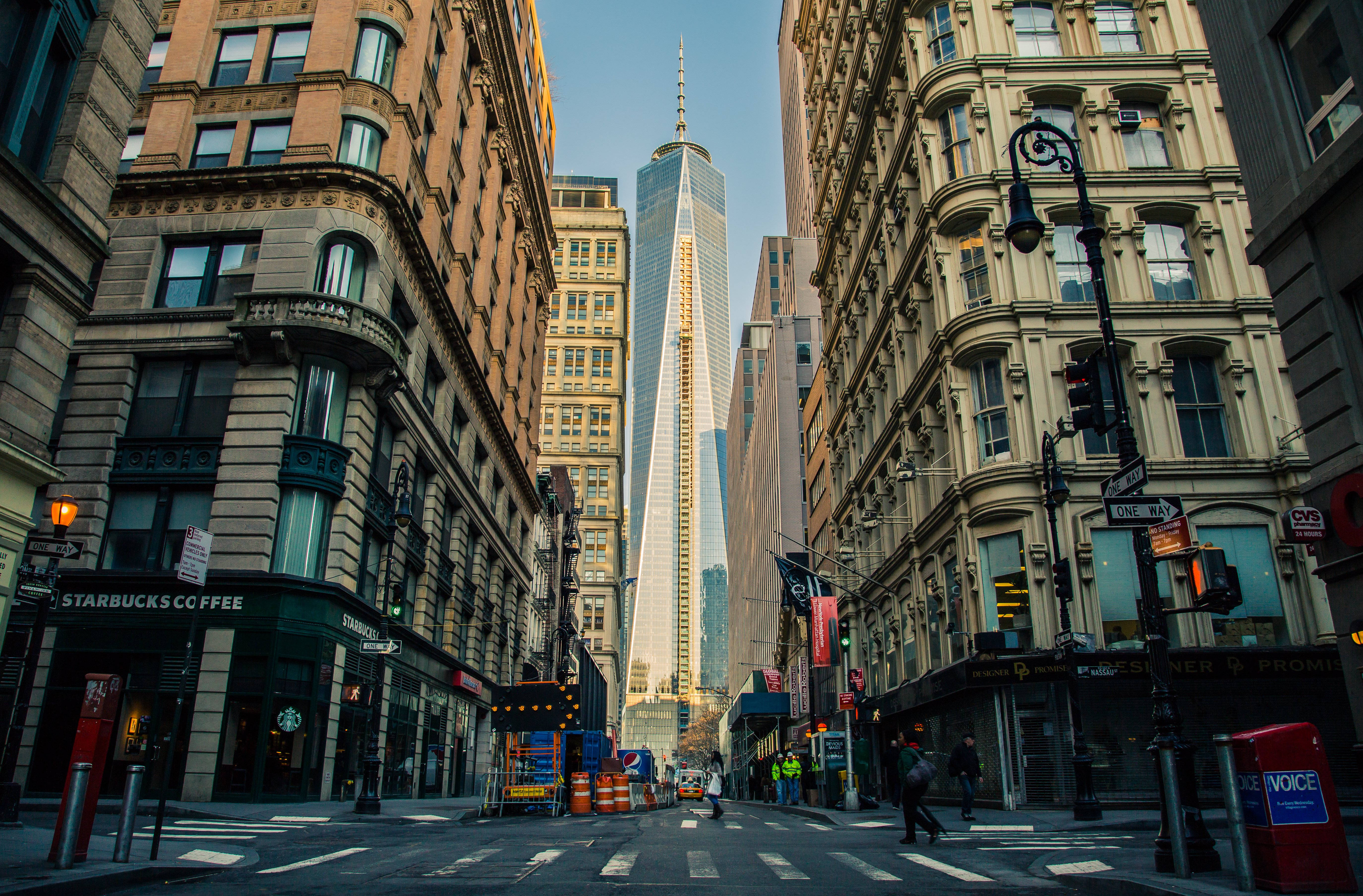 4K New York City 桌布 壁紙 — 一個低角度城市街景，由歷史建築物框住，自由塔刺穿天空。