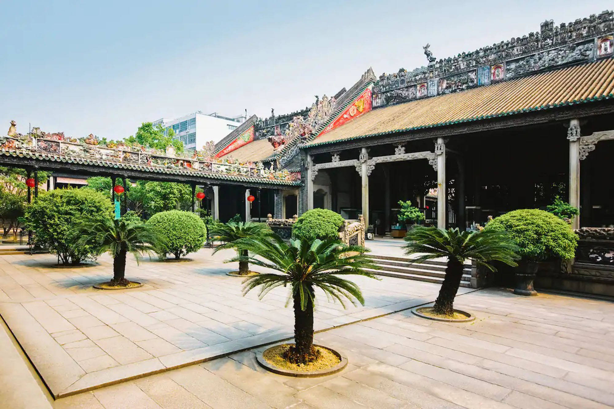 Guangzhou 桌布 壁紙 — 一個傳統中式寺廟庭院，擁有華麗的瓦頂和盆栽蘇鐵，在明亮的日光下。
