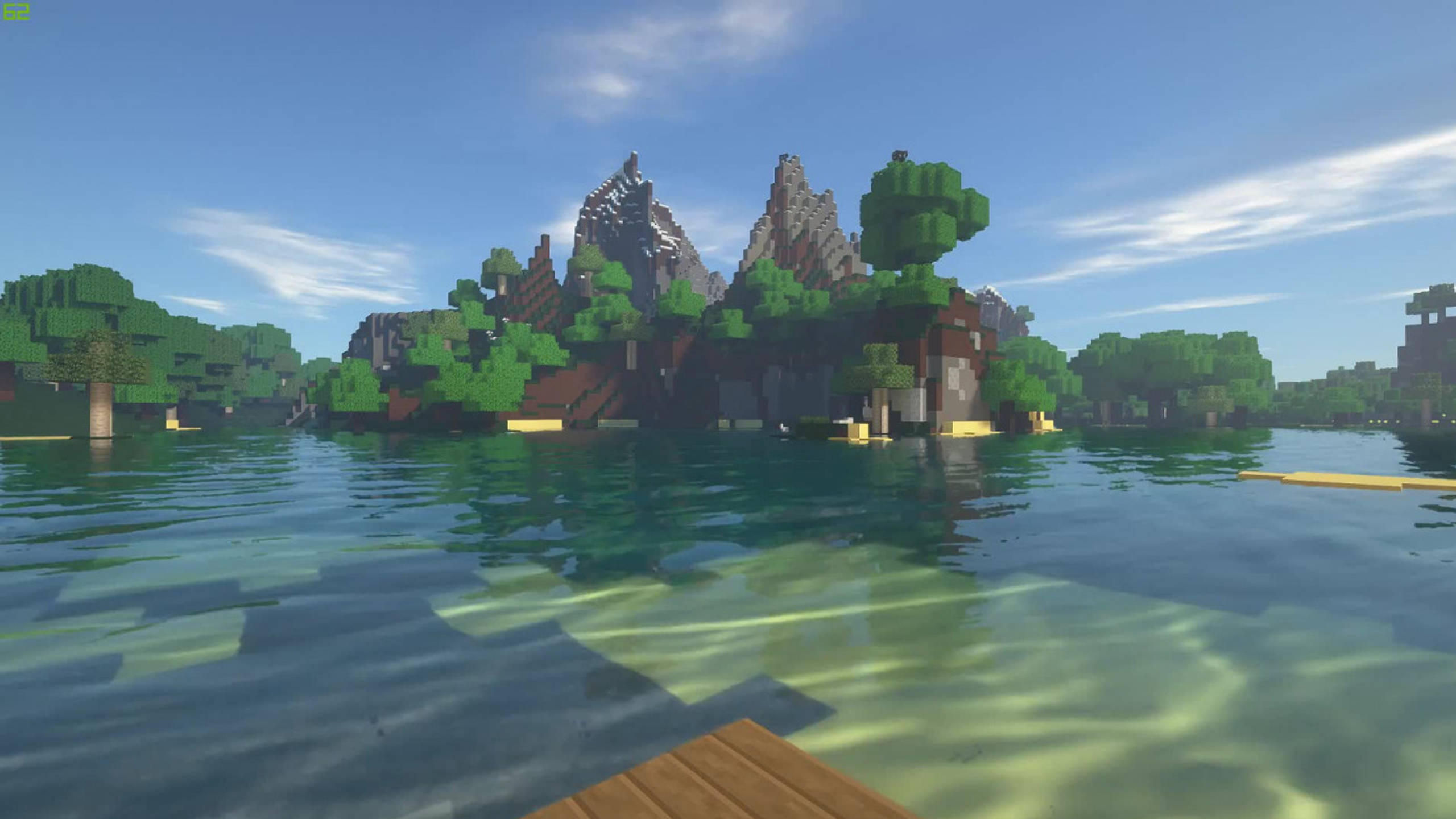 Minecraft Shaders 桌布 壁紙 — 一個像素化的Minecraft島嶼，有綠色樹木和岩石山峰，從清澈的藍色海水中升起，天空明亮。