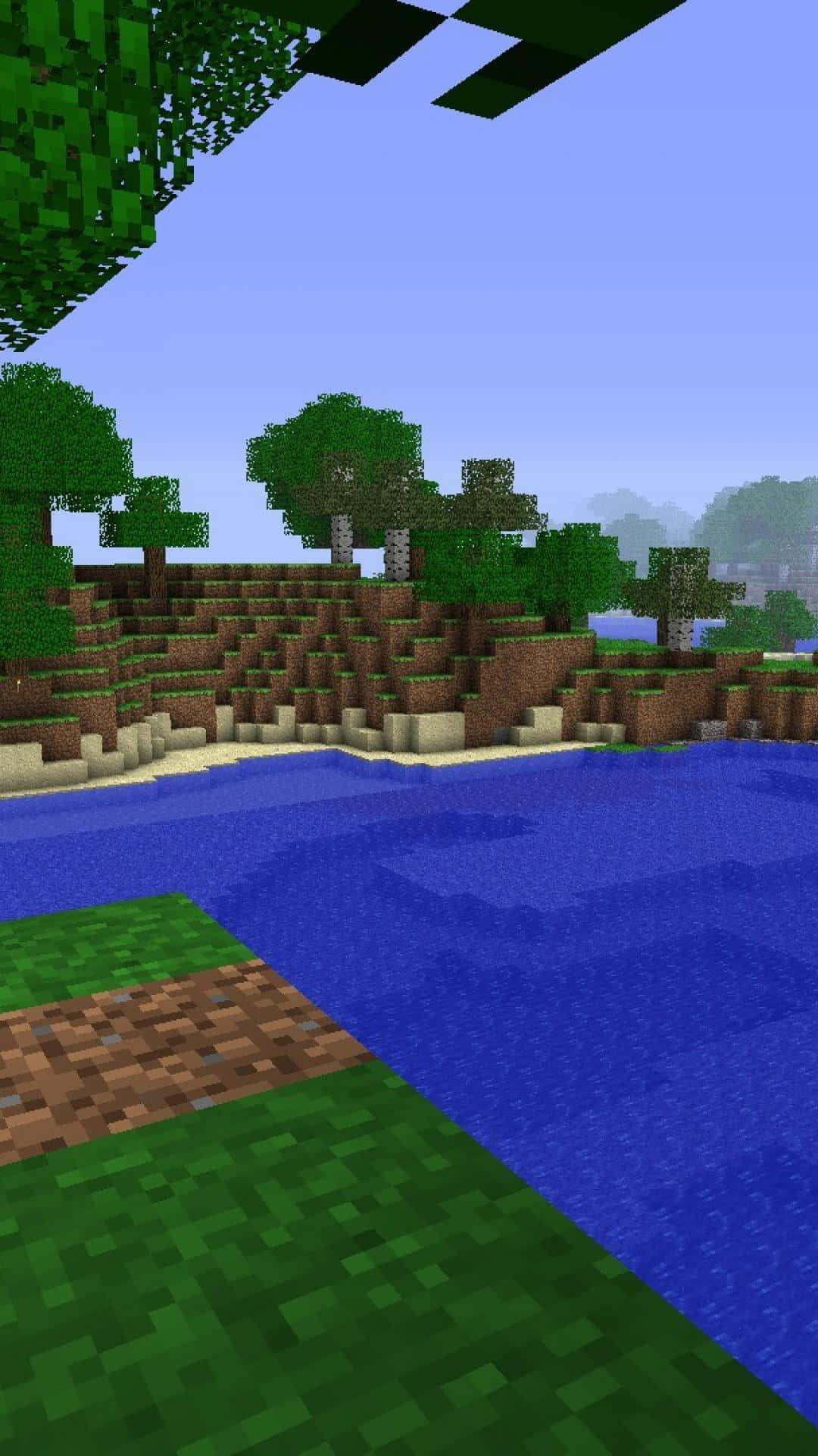 電玩遊戲 桌布 壁紙 — 一個像素化的Minecraft景觀，藍色河流流過綠色草地和棕色泥土山丘，有方塊狀的樹木，天空晴朗。