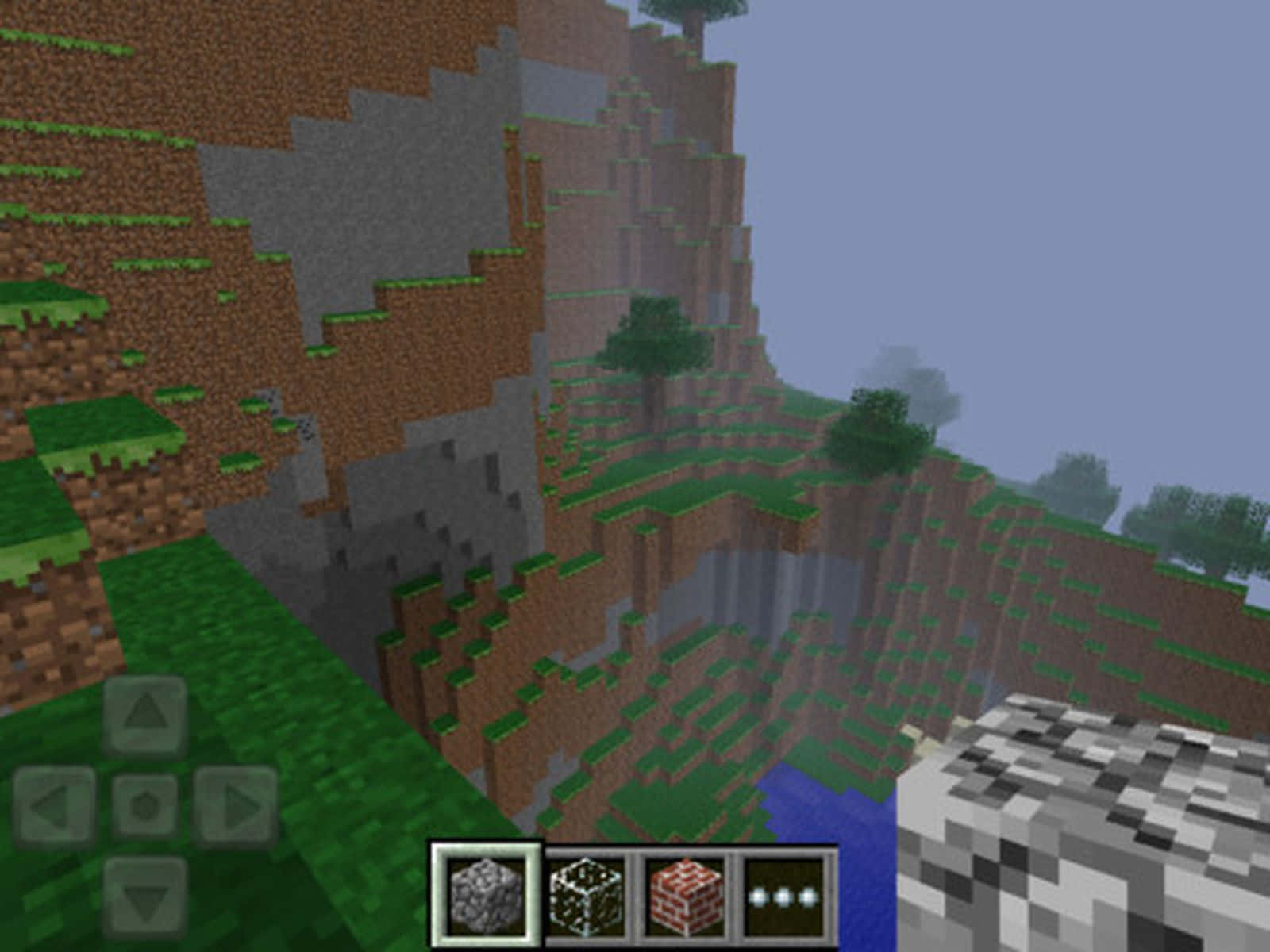 Minecraft Pocket Edition 桌布 壁紙 — 一個像素化的Minecraft景觀，有塊狀懸崖、草地、樹木和一條河流，天空蒼白。