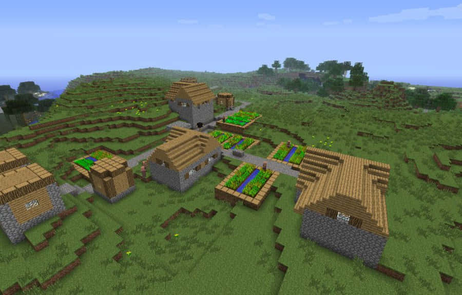 Minecraft Villages 桌布 壁紙 — 一個像素化的Minecraft村莊坐落在起伏的綠色山丘上，有石屋和梯田農地，天空晴朗蔚藍。