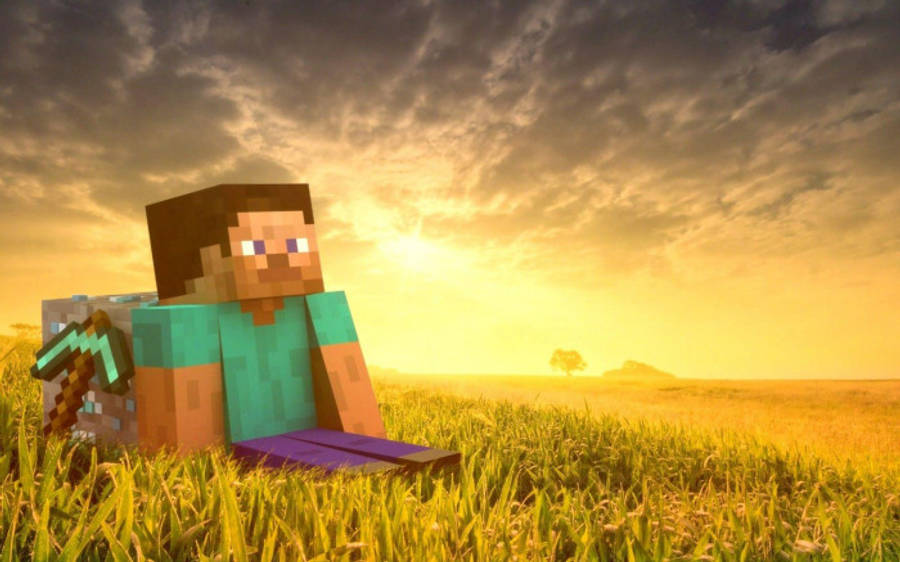 我的世界 史蒂夫 桌布 壁紙 — 一個像素化的Minecraft角色坐在日落時分的草地上，在戲劇性的金色天空下拿著鎬。