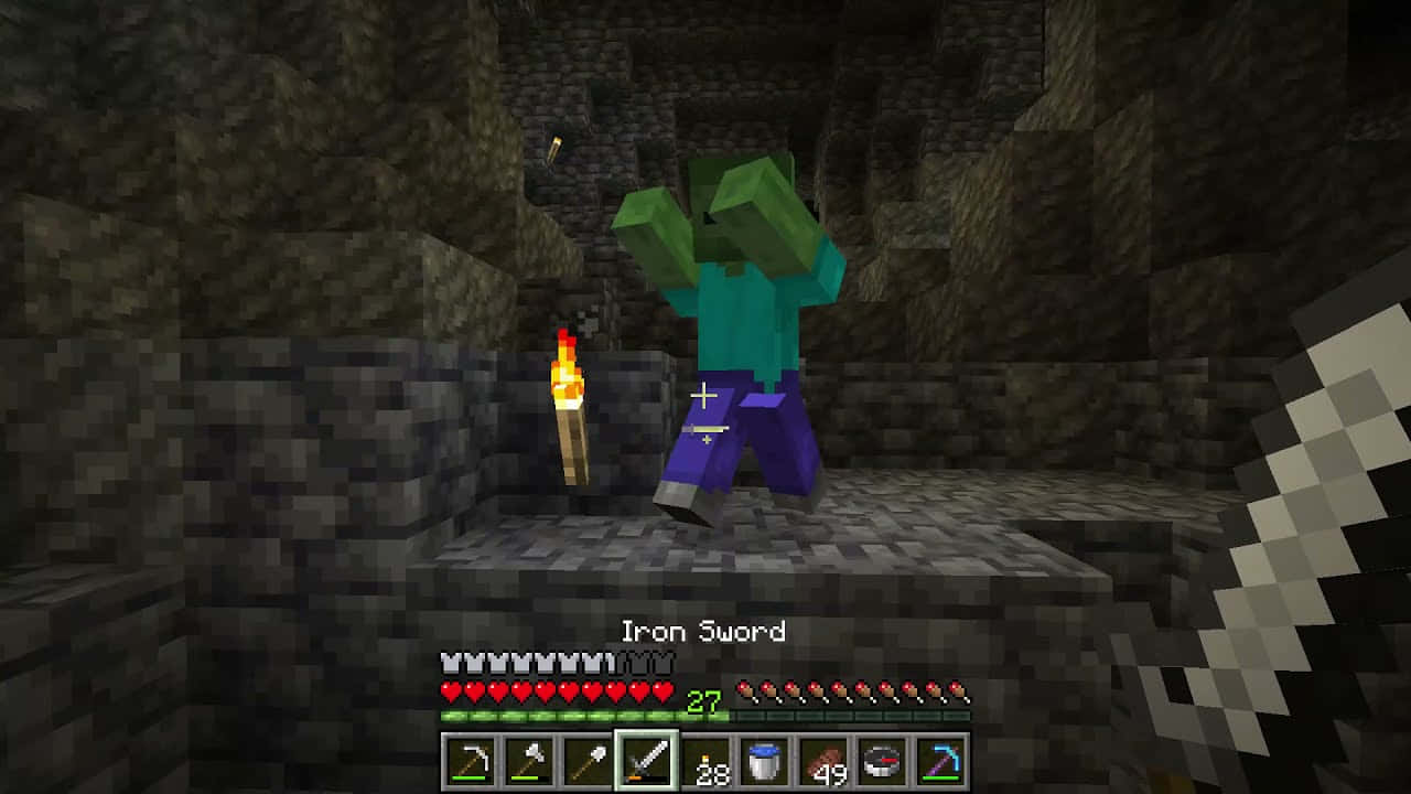 Minecraft Zombie 桌布 壁紙 — 一個像素化的殭屍在Minecraft洞穴中拿著火炬，而玩家以第一人稱視角揮動鐵劍。