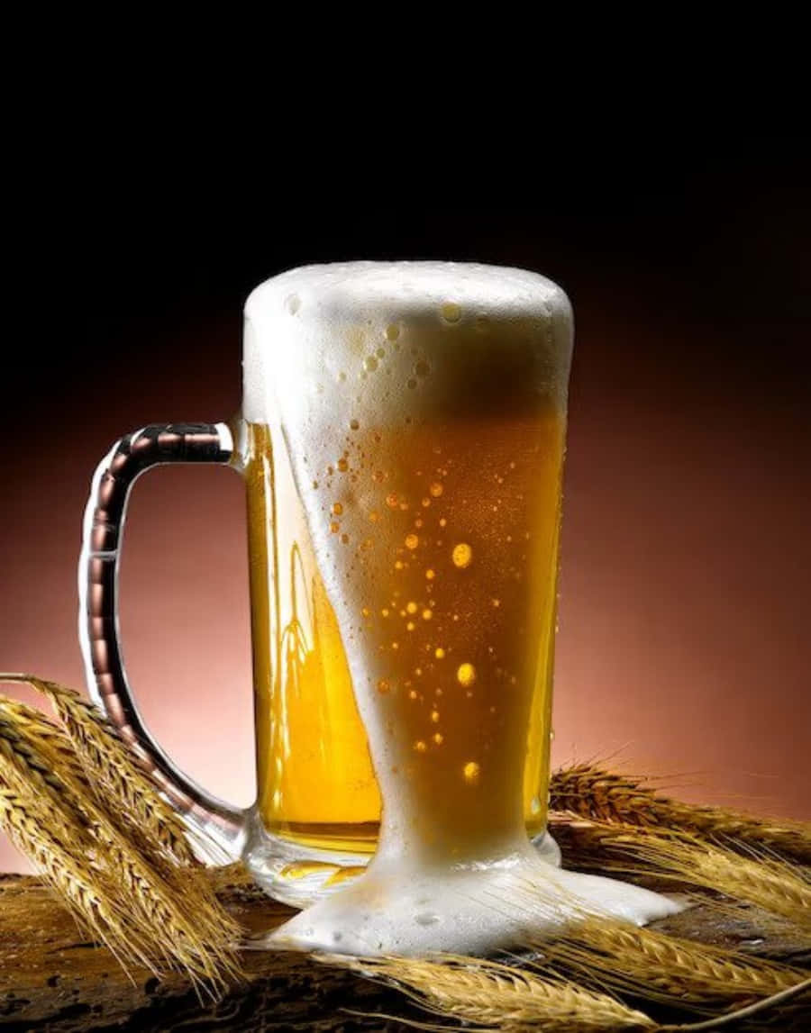 Beer 桌布 壁紙 — 一個充滿泡沫和氣泡的金色啤酒杯放在小麥稈上，背景是深色漸變。
