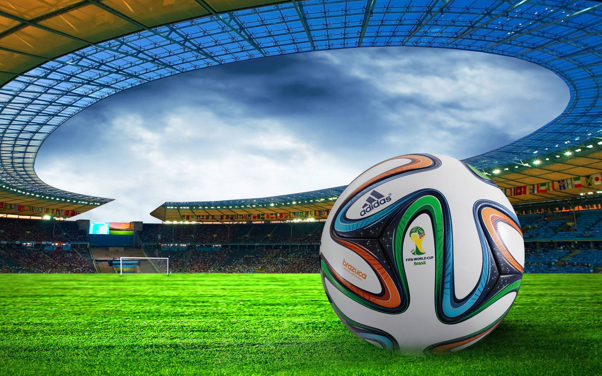 World 桌布 壁紙 — 一個充滿活力的 Brazuca 足球放在一個巨大體育場的茂密綠色球場上，天空烏雲密佈，氣氛戲劇化。