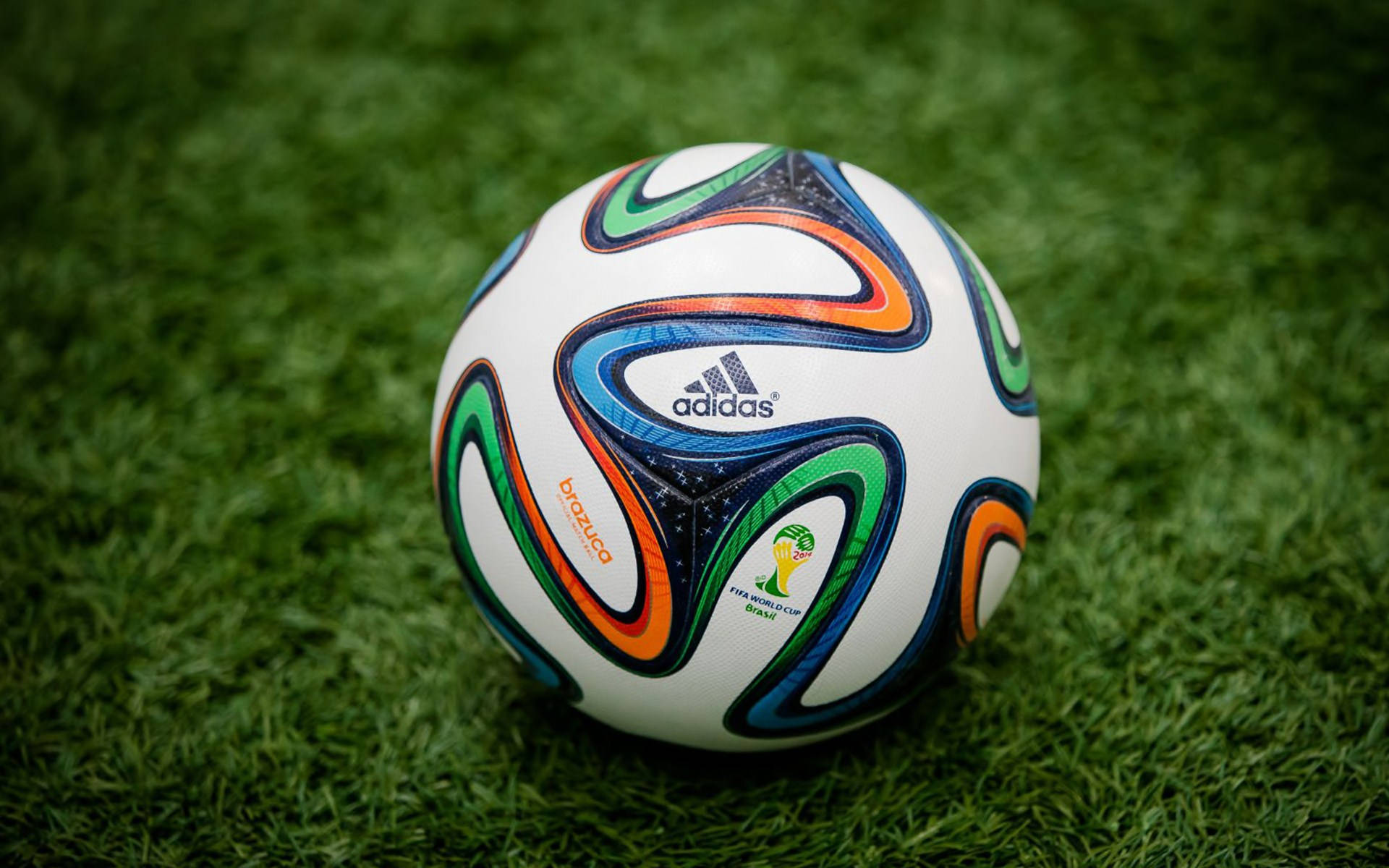 World 桌布 壁紙 — 一個充滿活力的 Brazuca 足球在明亮的日光下，躺在茂密的綠草地上。