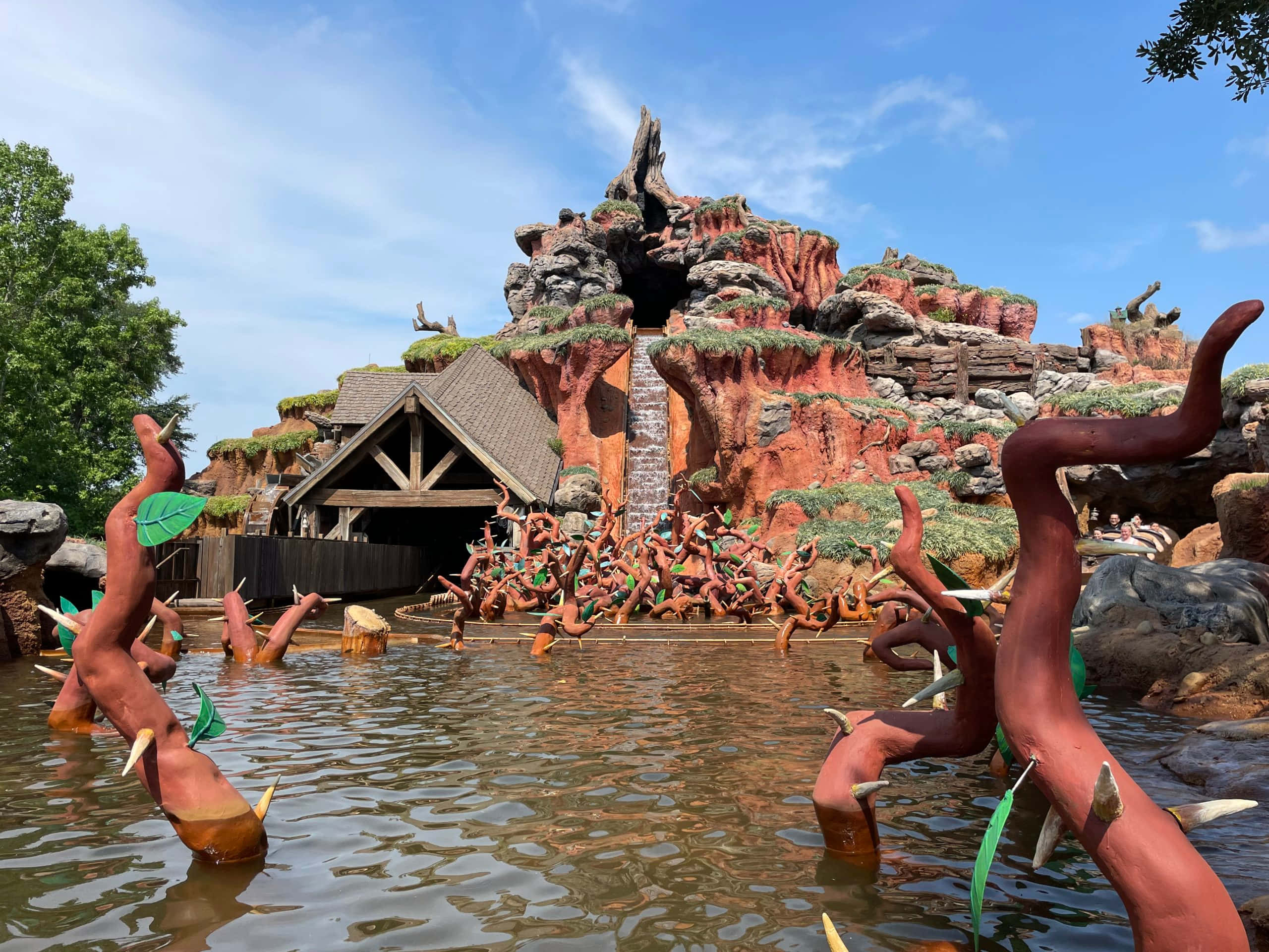 Splash Mountain 桌布 壁紙 — 一個充滿活力的主題公園景點，設有位於岩石峽谷中的木結構，水池中有水和風格化的樹狀雕塑。