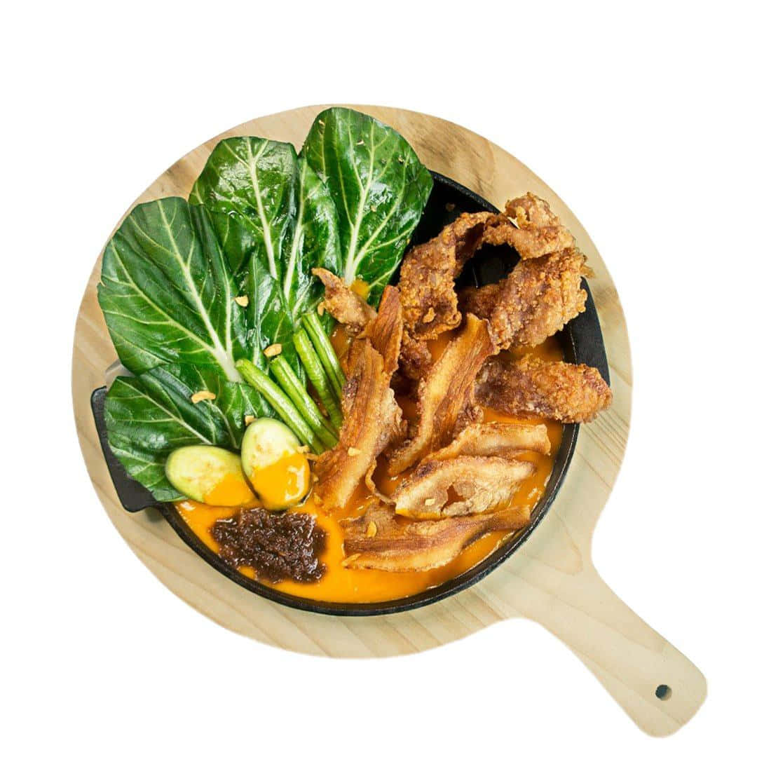 meat 桌布 壁紙 — 一個充滿活力的俯拍鏡頭，展示了一個鑄鐵煎鍋，裡面裝滿了酥脆的炸雞、小白菜、青豆和濃郁的橙色醬汁，放在木板上。