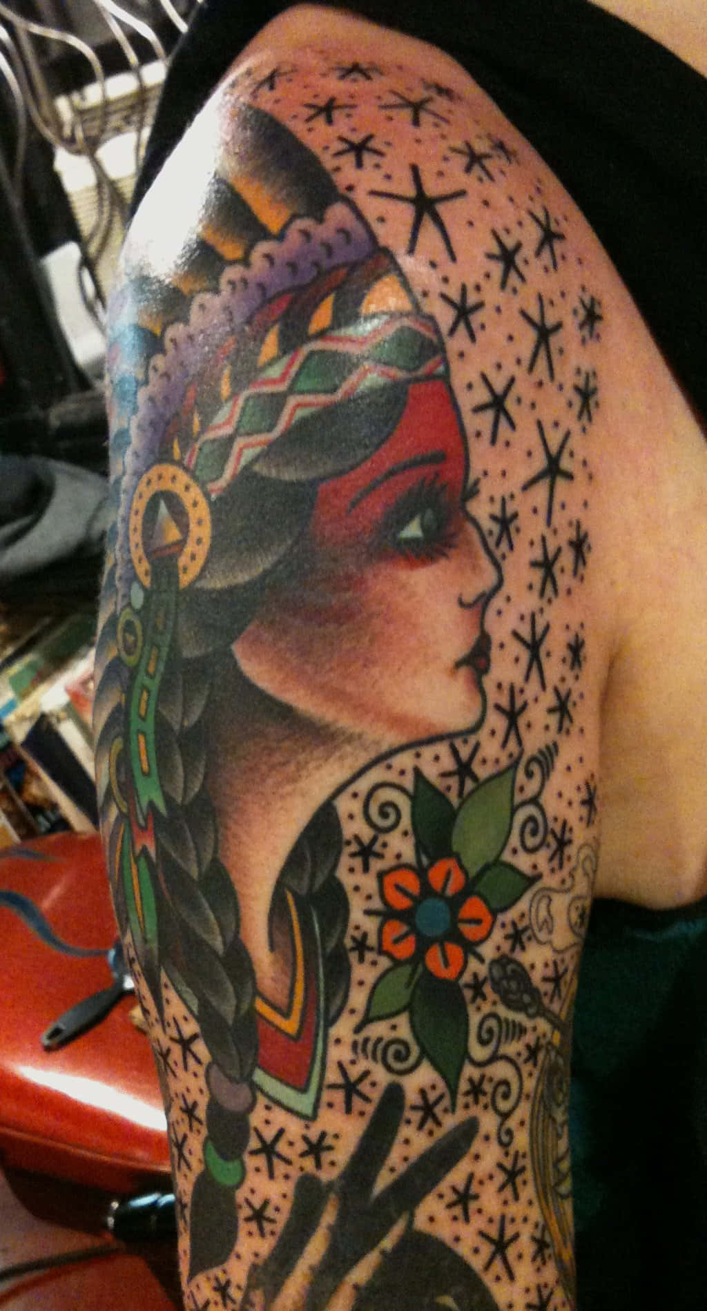 Tattoo 桌布 壁紙 — 一個充滿活力的刺青，描繪了一位辮子頭髮和星星圖案的女人，以大膽的色彩和複雜的細節覆蓋了手臂。