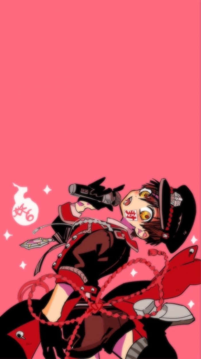 Hanako Kun 桌布 壁紙 — 一個充滿活力的動漫角色，身穿紅黑服飾，帶有鏈條和帽子，在純粉紅色背景前手持槍支。
