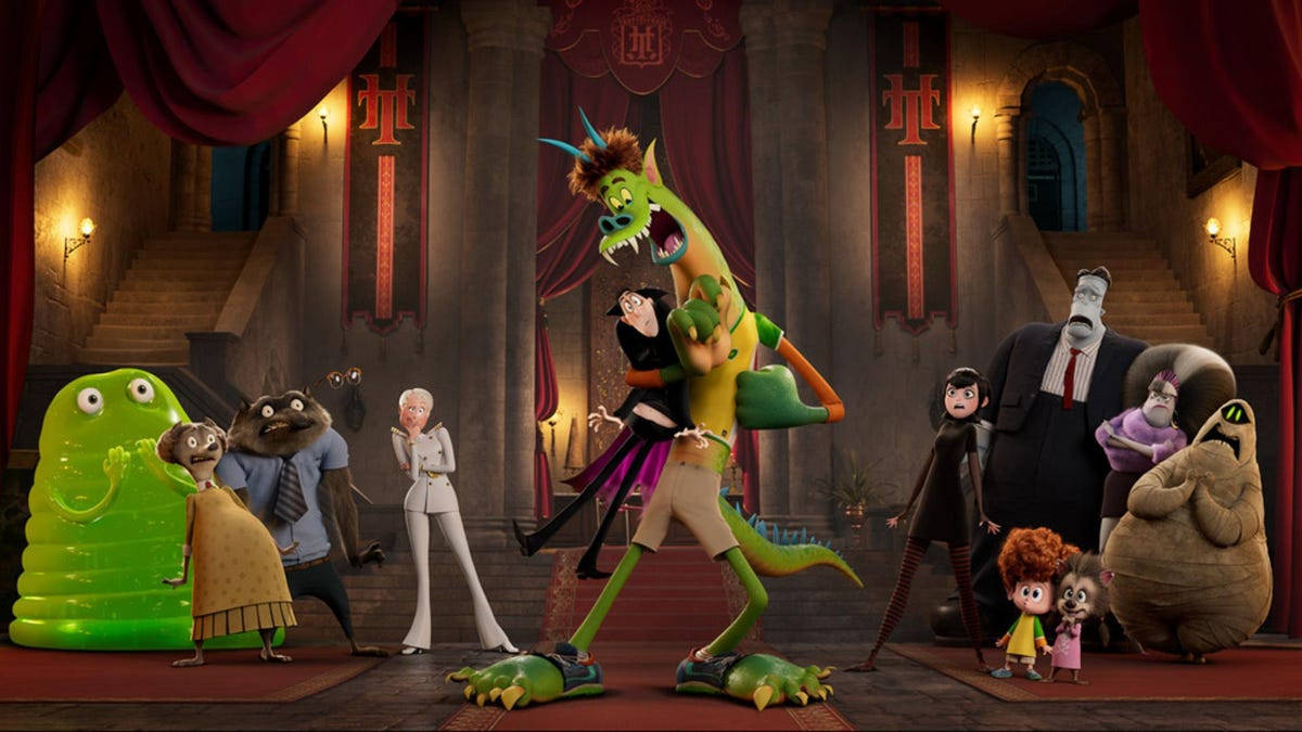 hotel transylvania transformania 桌布 壁紙 — 一個充滿活力的動畫場景，描繪一隻綠色龍狀生物在宏偉劇院中與一群古怪的怪物角色跳舞。