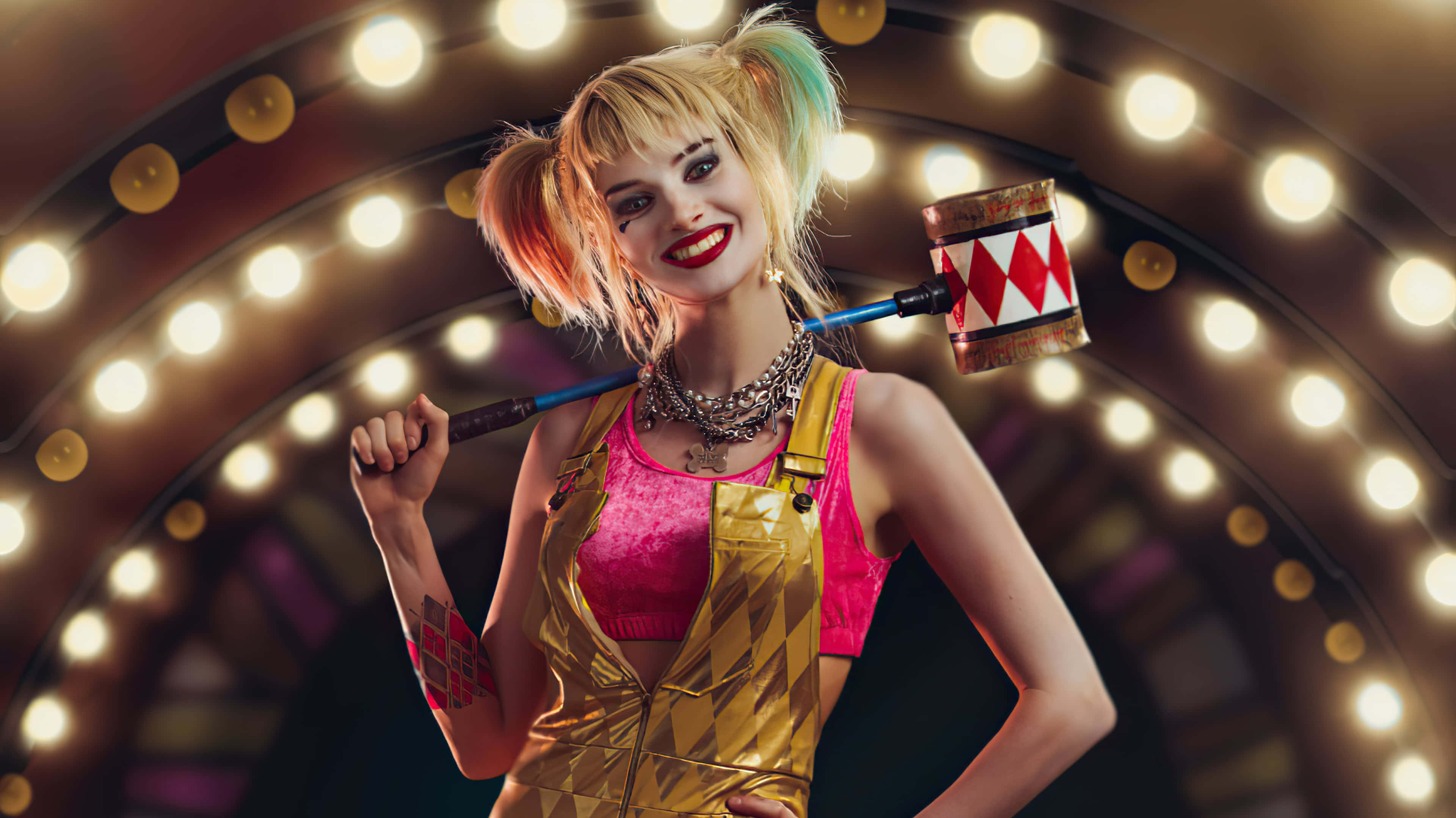 Harley Quinn Hammer 桌布 壁紙 — 一個充滿活力的哈莉·奎茵，身穿金色和粉紅色服裝，在閃爍的燈光背景前自信地擺姿勢，手持大錘。