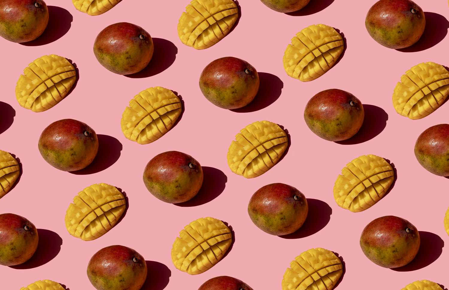 Mango 桌布 壁紙 — 一個充滿活力的圖案，由完整和劃開的芒果整齊排列在柔和的粉紅色背景上，帶有鮮明的陰影。