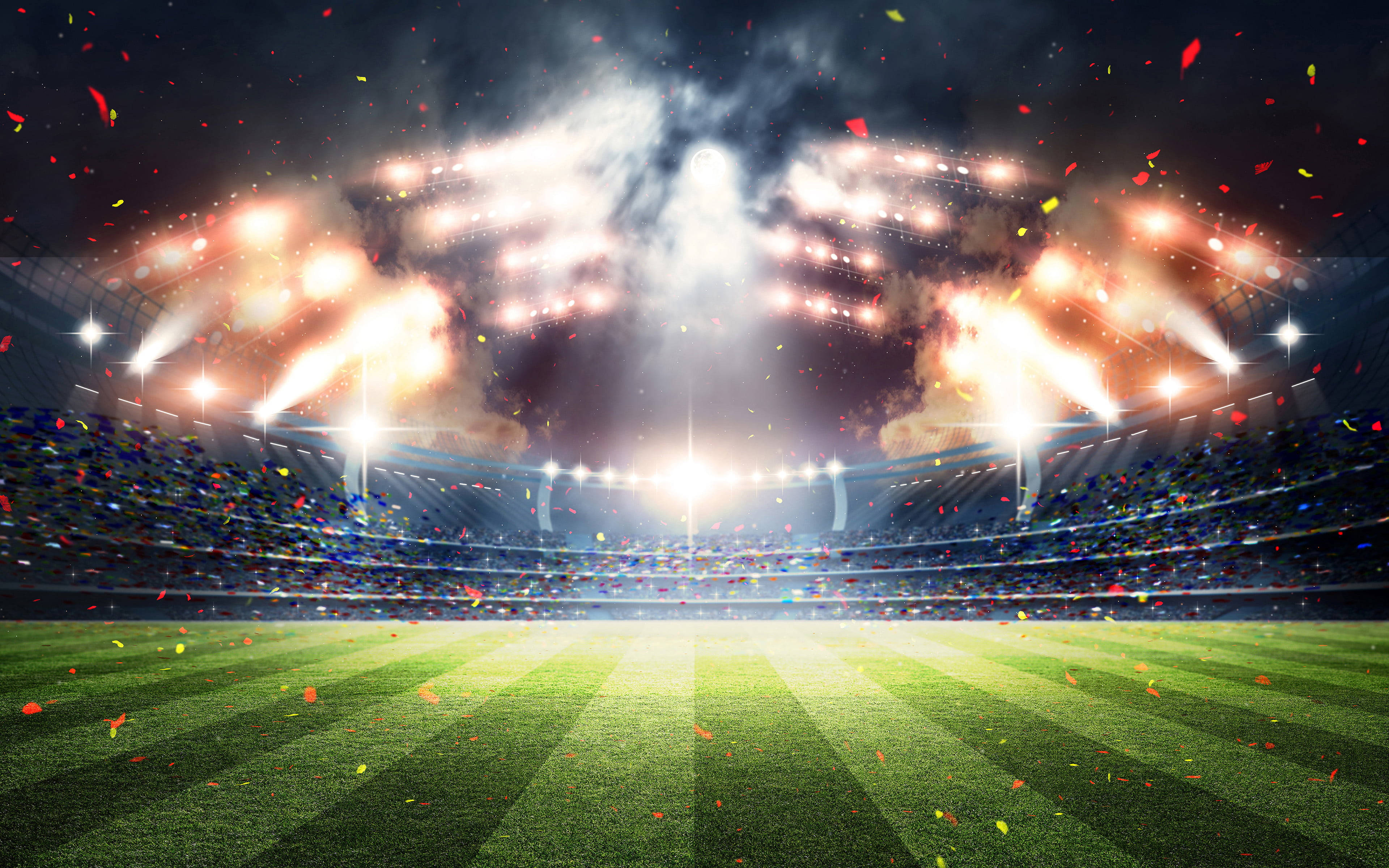 Stadium 桌布 壁紙 — 一個充滿活力的夜間體育館，被明亮的聚光燈照亮，五彩紙屑飄落在綠色場地上。