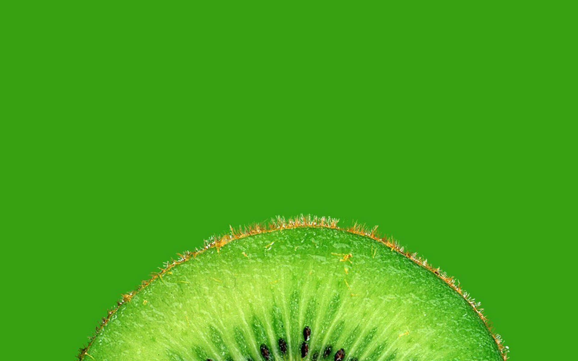 Kiwi 桌布 壁紙 — 一個充滿活力的奇異果切片特寫，以純綠色背景襯托，展現其絨毛外皮和多汁內部。