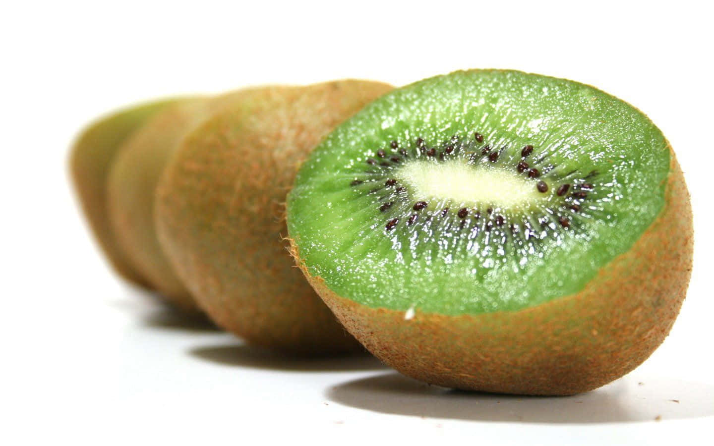 Kiwi 桌布 壁紙 — 一個充滿活力的奇異果橫切面，在乾淨的白色背景上展現出多汁的綠色果肉和黑色種子。