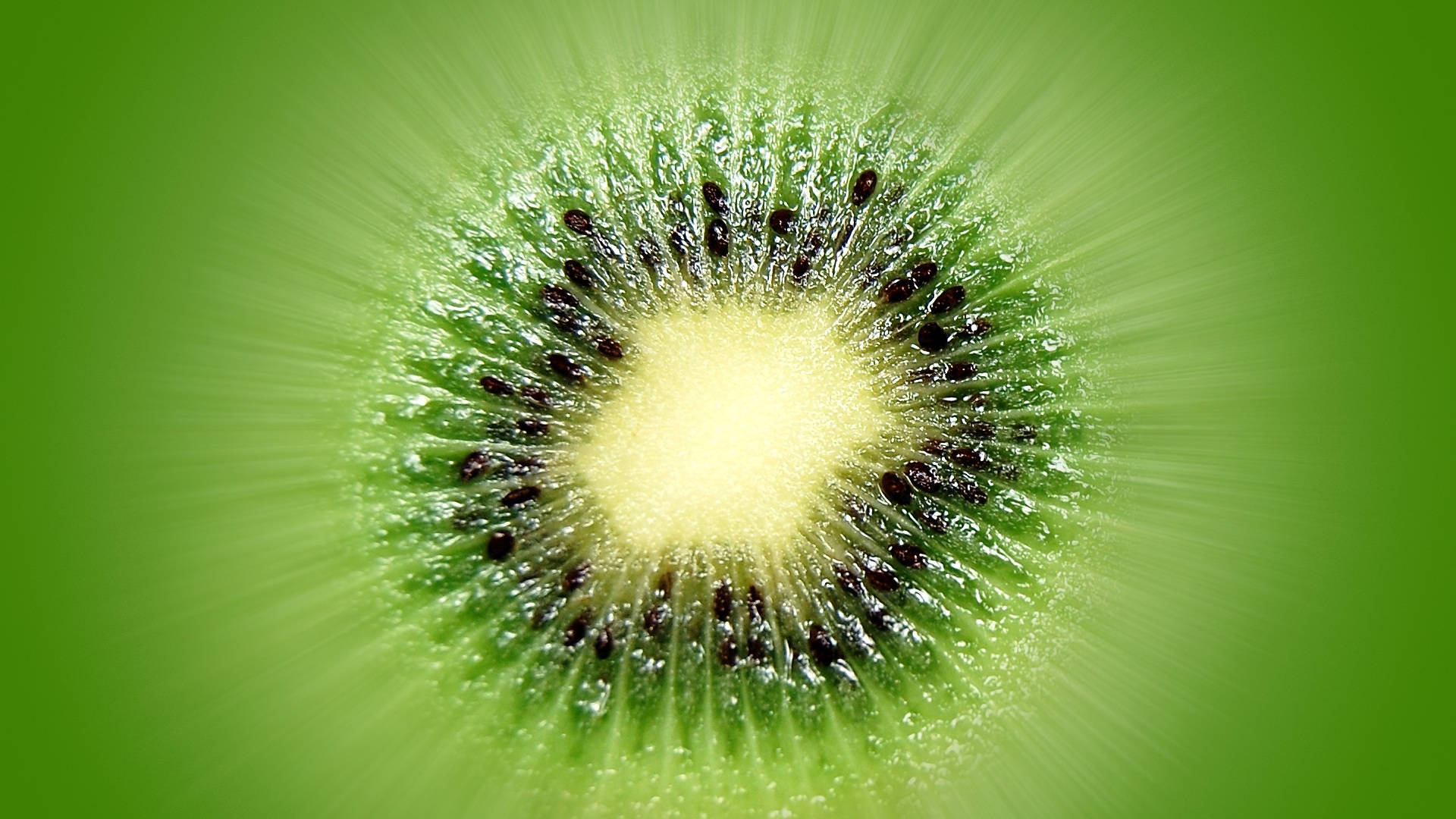 Kiwi 桌布 壁紙 — 一個充滿活力的奇異果橫切面，散發出綠色色調和黑色種子，映襯在發光的綠色背景上。