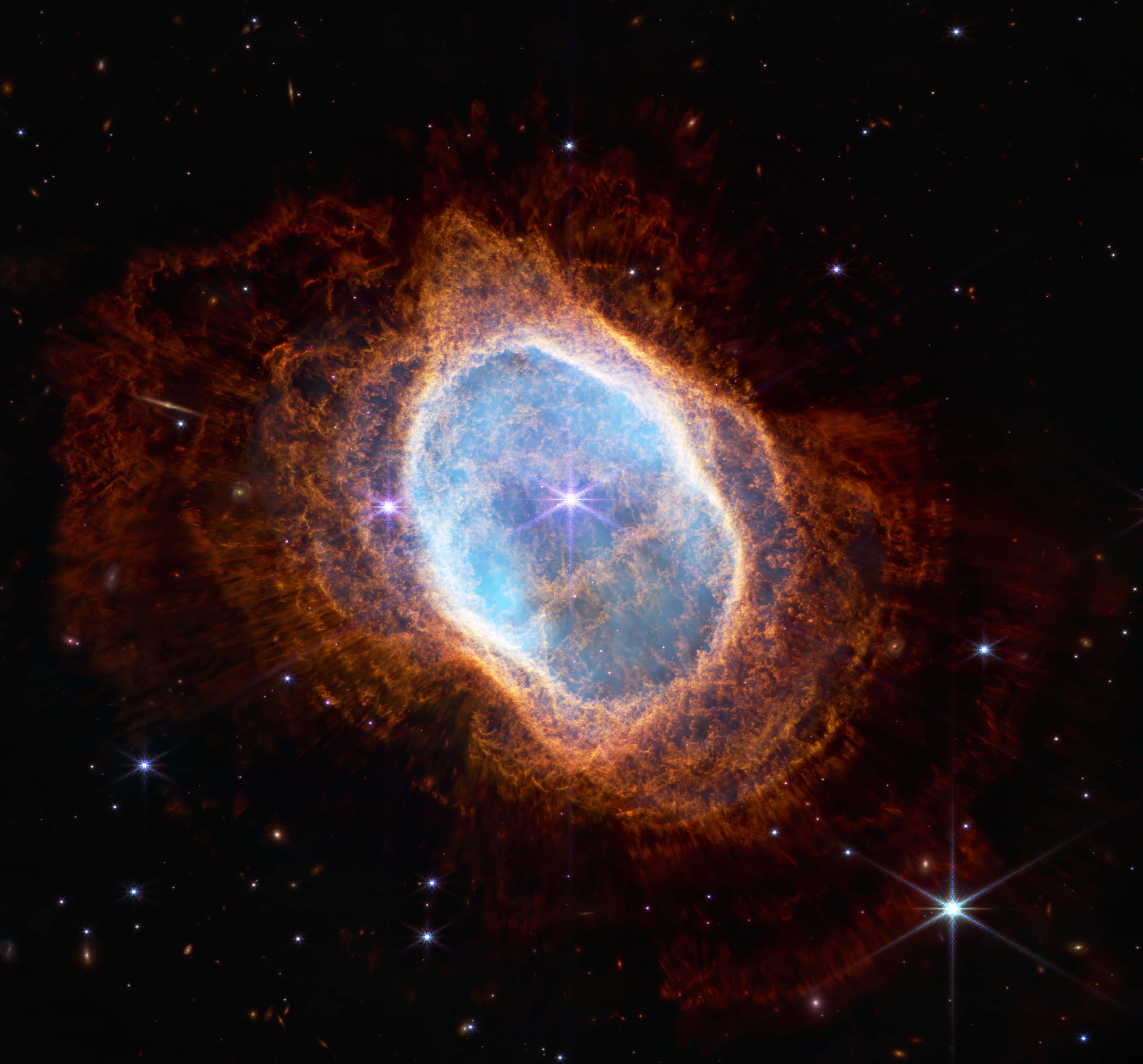 桌布 壁紙 — 一個充滿活力的宇宙星雲，中心發出藍色光芒，被熾熱的橙色觸手環繞，背景是星空。