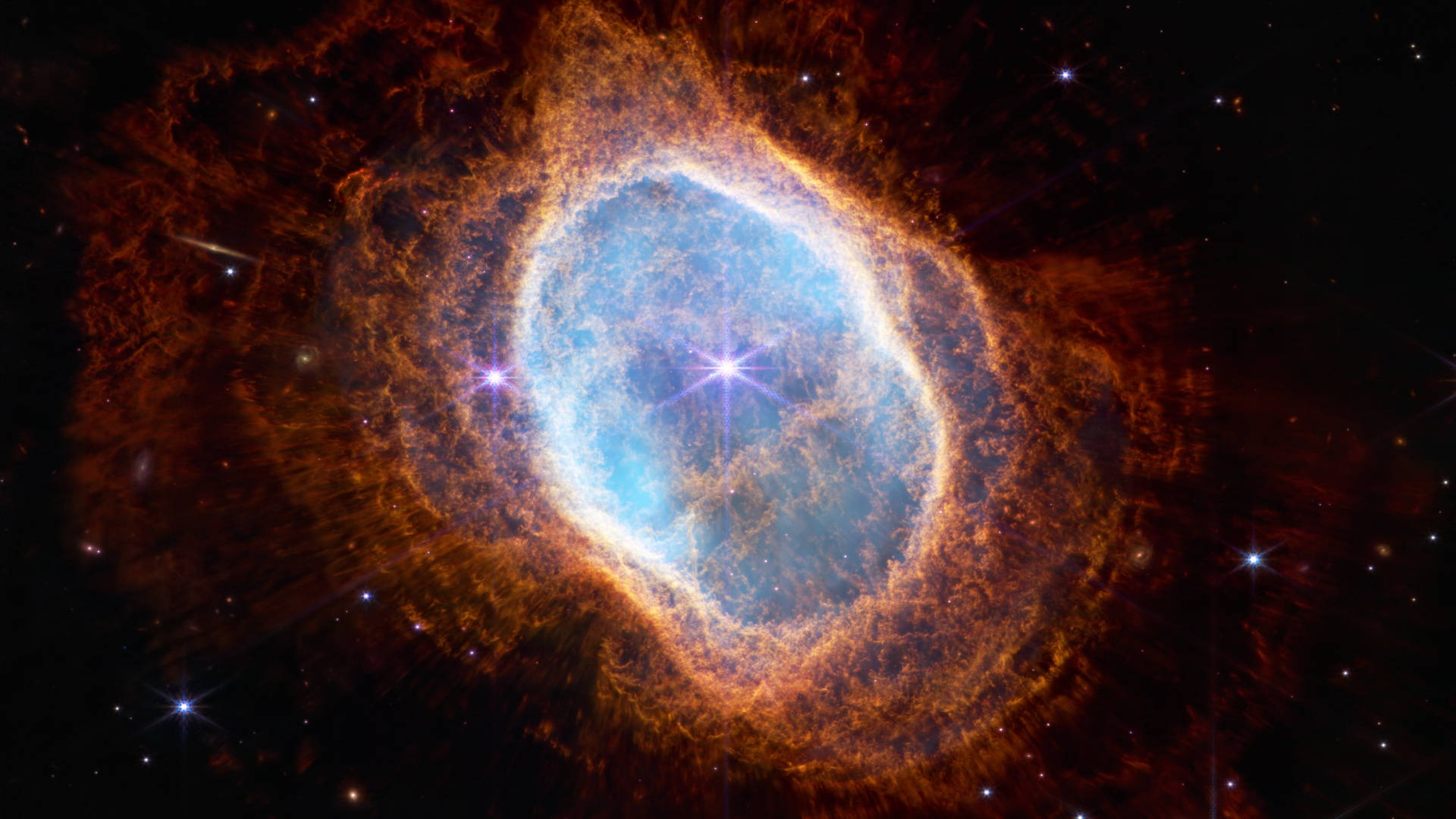 宇宙美學 桌布 壁紙 — 一個充滿活力的宇宙星雲，中心發出藍色光芒，被熾熱的橙色觸手環繞，背景是繁星點點的黑色虛空。