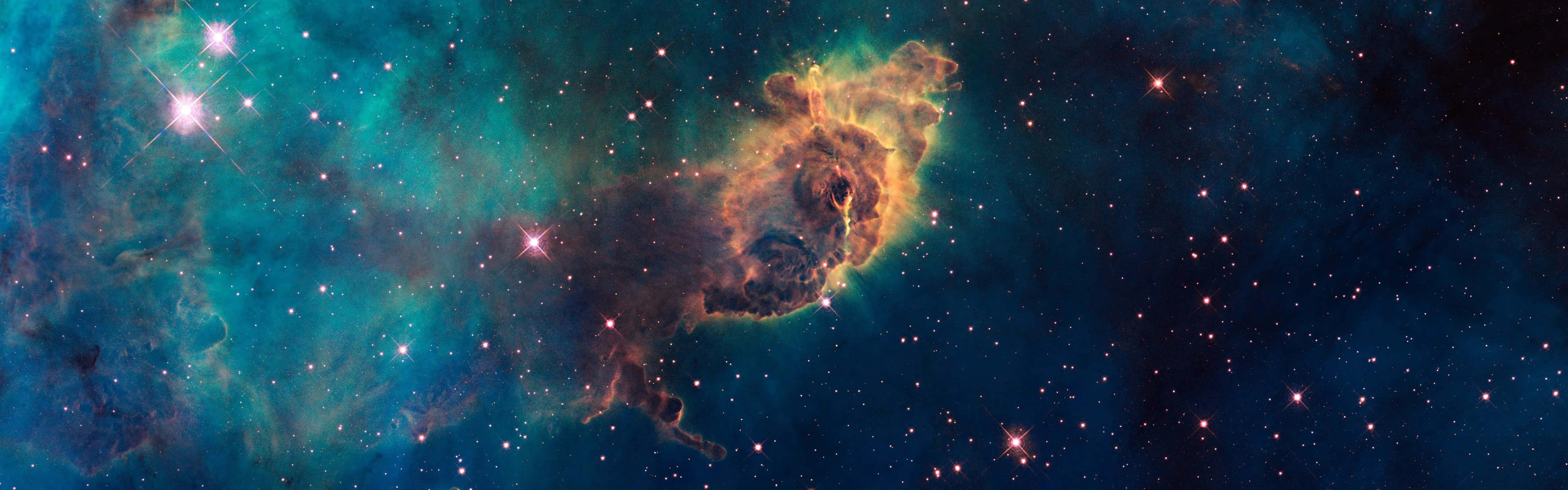 銀河 桌布 壁紙 — 一個充滿活力的宇宙星雲，在深空的星場背景下散發著青綠色和橙色的色調。