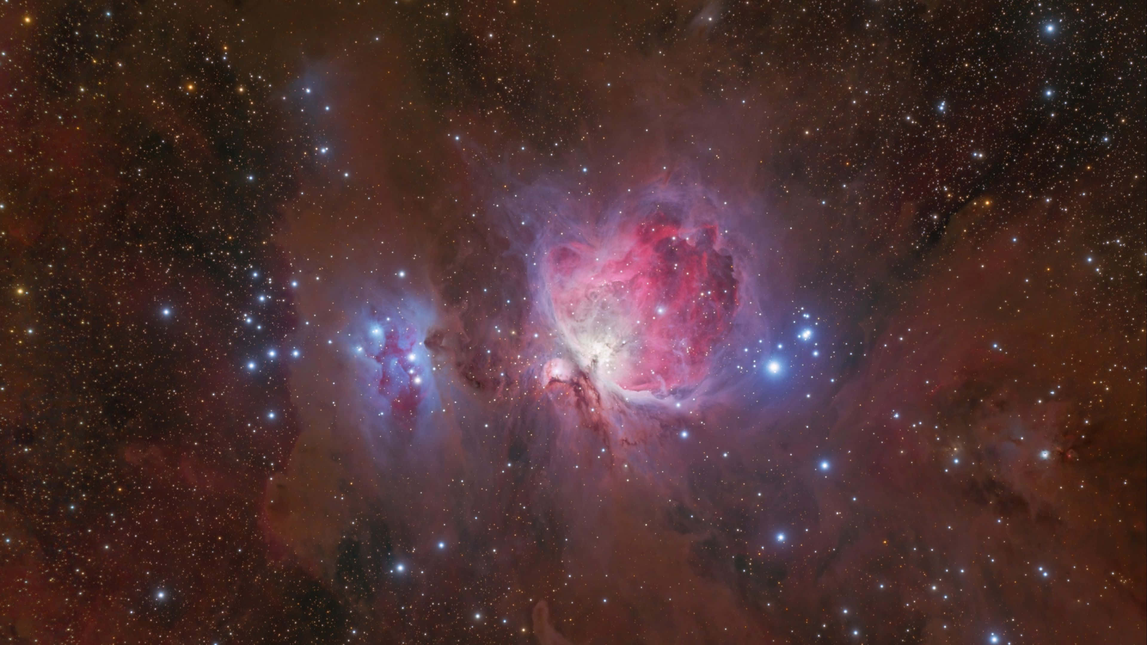 Orion 桌布 壁紙 — 一個充滿活力的宇宙星雲，在深空的星場背景下散發出粉紅色和藍色的色調。