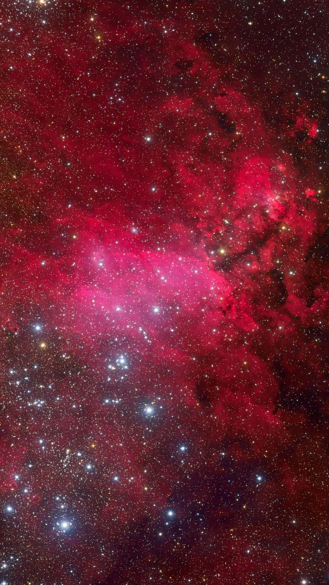 紅色 iPhone 桌布 壁紙 — 一個充滿活力的宇宙星雲，在深紅色和粉紅色中發光，黑暗虛空中散佈著明亮的星星。