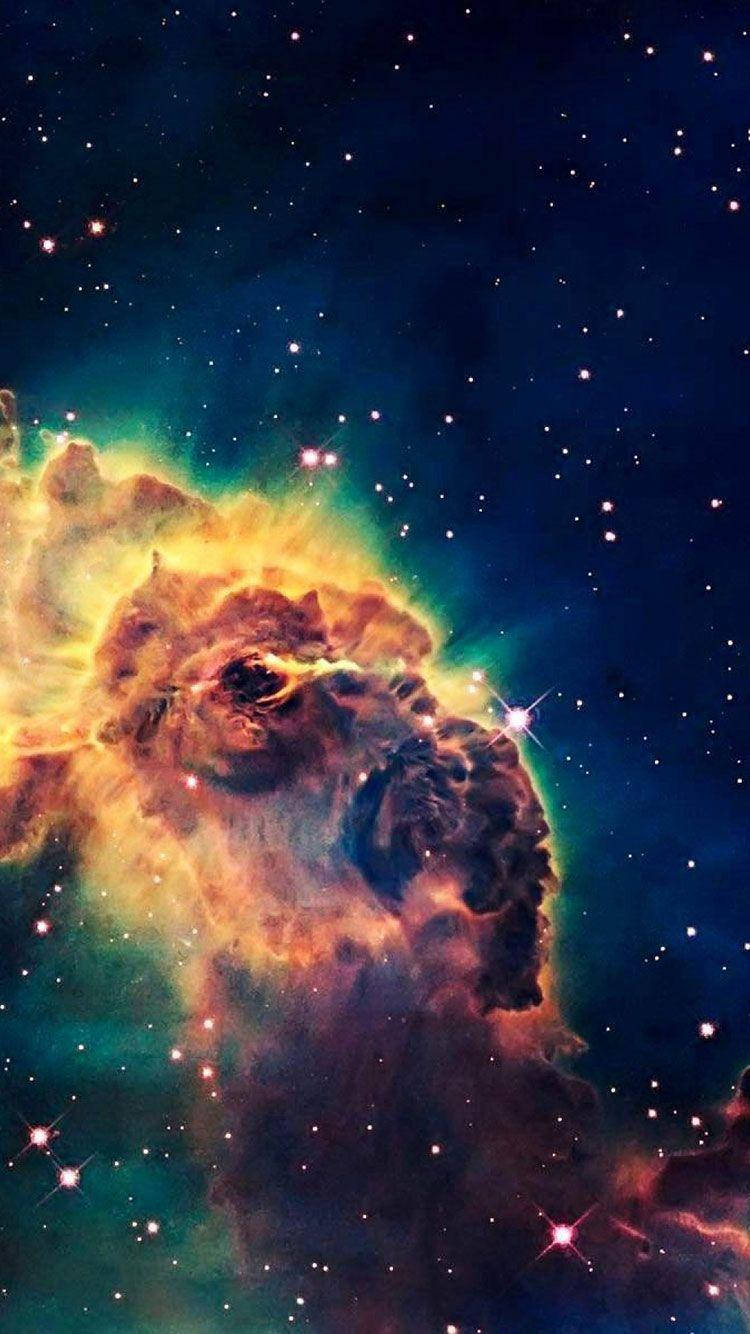 銀河 iPhone 桌布 壁紙 — 一個充滿活力的宇宙星雲，在繁星點點的深藍色夜空中散發出火熱的橙色和藍綠色調。