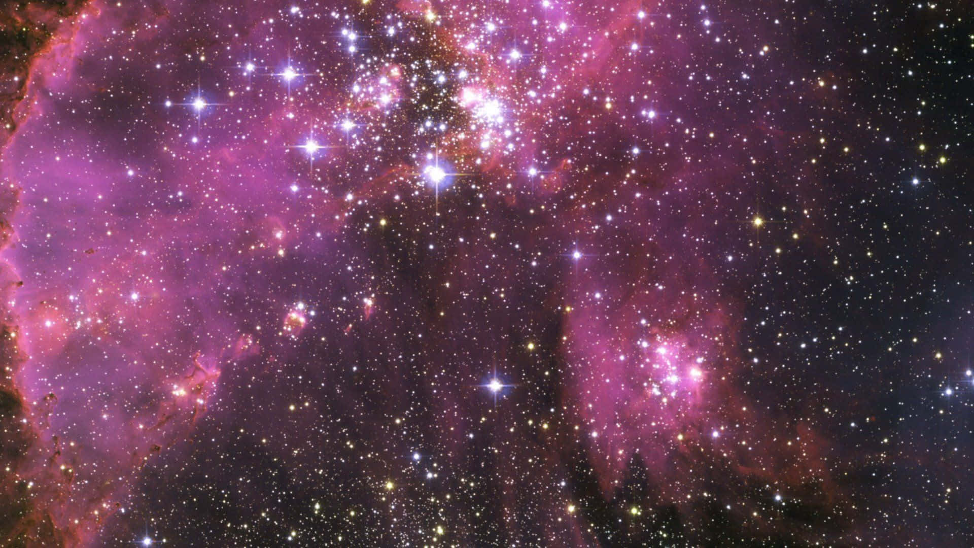 粉紅銀河 桌布 壁紙 — 一個充滿活力的宇宙星雲，在黑暗虛空中散發著粉紅色和紫色的色調，點綴著無數閃爍的星星。