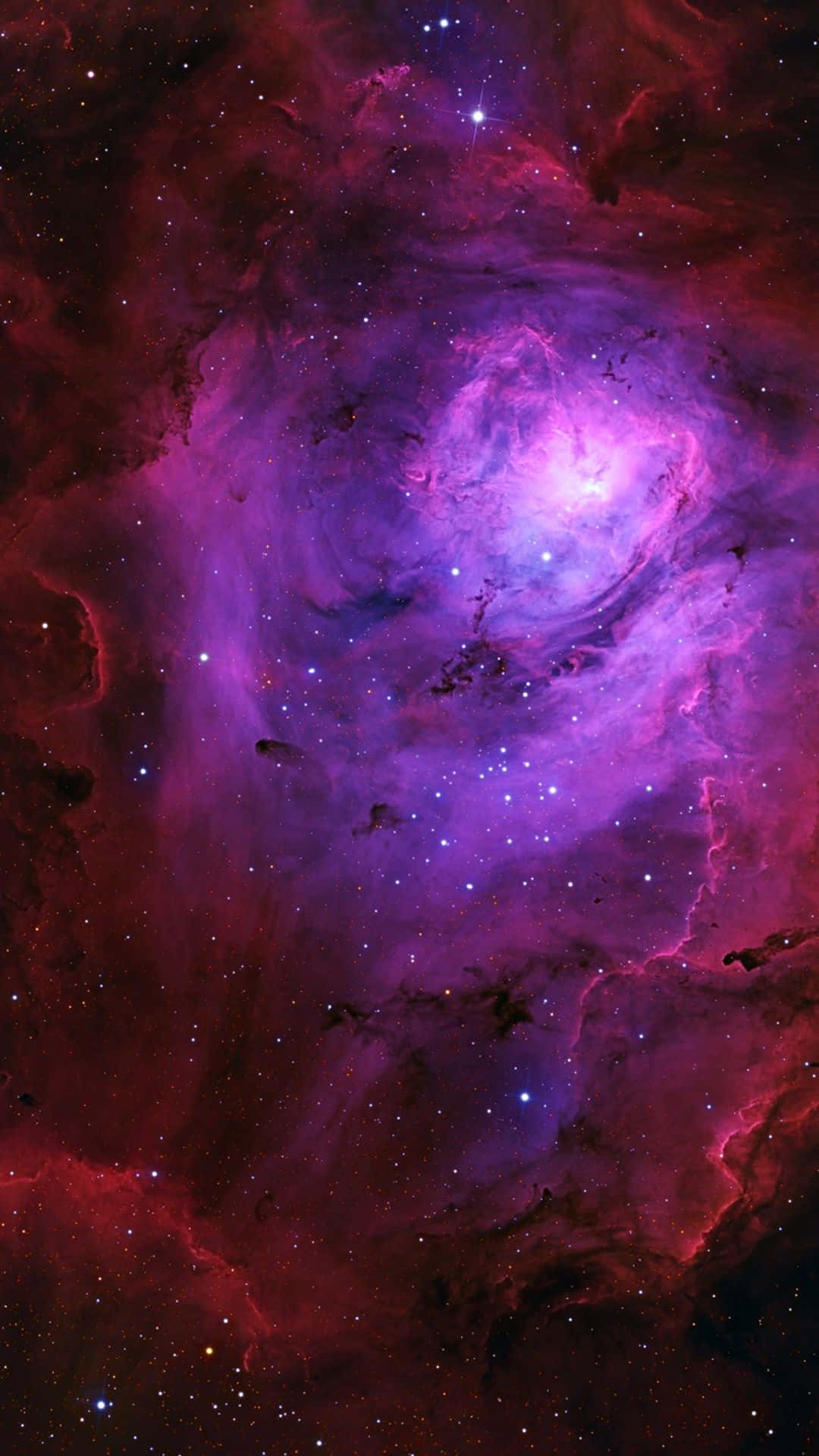 銀河 桌布 壁紙 — 一個充滿活力的宇宙星雲，在黑暗虛空中旋轉著發光的紫色和深紅色雲朵，點綴著閃爍的星星。