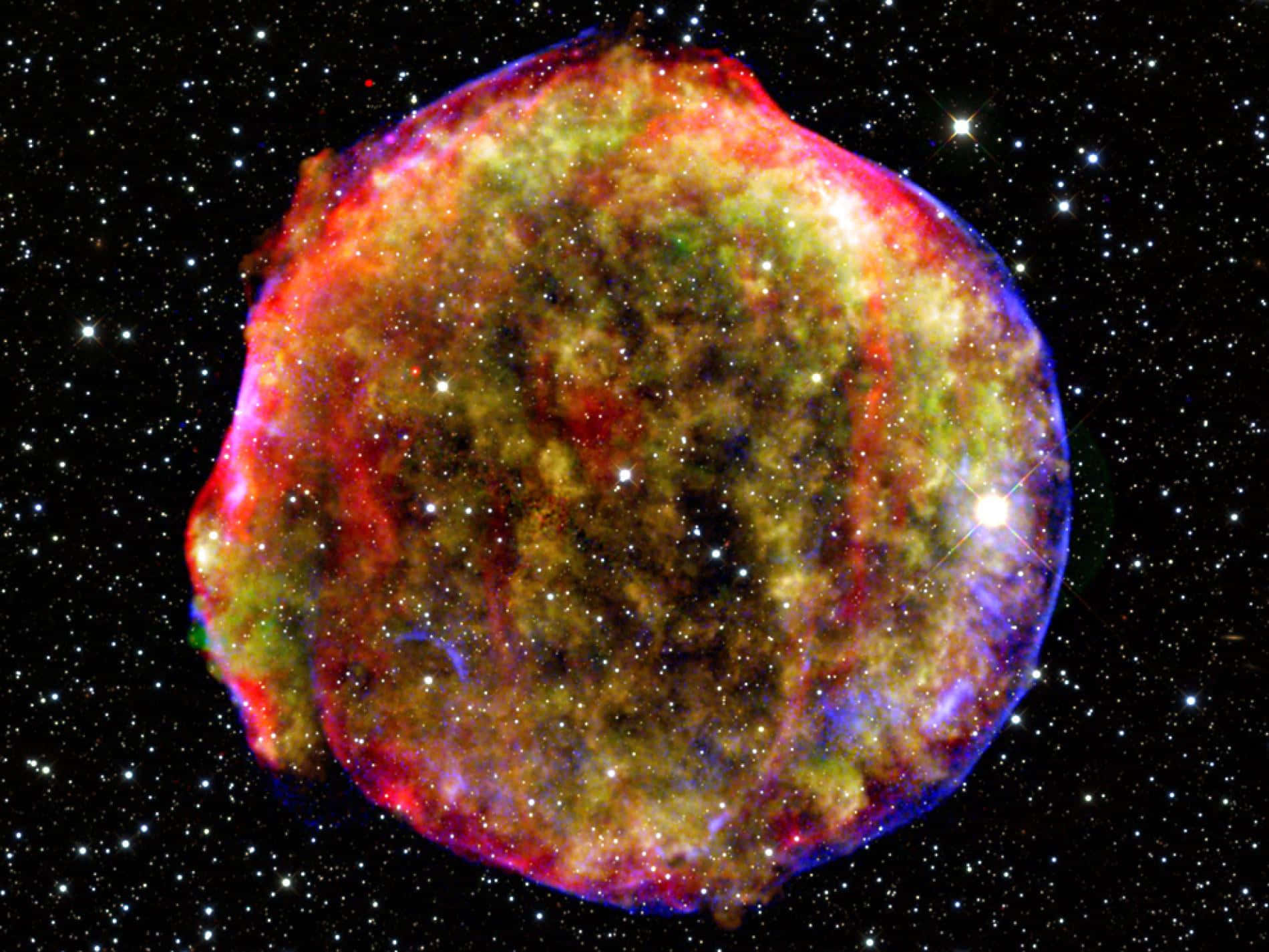Supernova Explosion 桌布 壁紙 — 一個充滿活力的宇宙星雲，旋轉的紅色、綠色和藍色氣體在星空中閃耀。