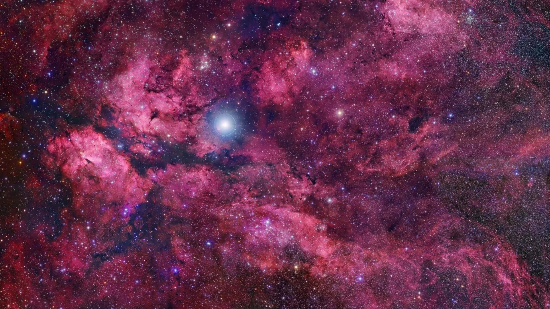 桌布 壁紙 — 一個充滿活力的宇宙星雲，由洋紅色和深紅色的雲團構成，點綴著閃爍的星星和一顆明亮的中心星。