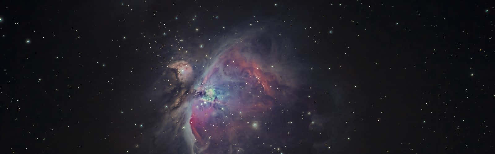 Dark Galaxy 桌布 壁紙 — 一個充滿活力的宇宙星雲在深空星場中散發著紅色、紫色和藍色的光芒。