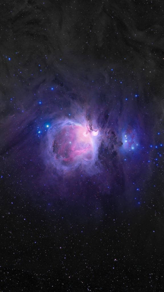 紫色 iPhone 桌布 壁紙 — 一個充滿活力的宇宙星雲在深空的星場中散發出粉紅色和藍色的光芒。