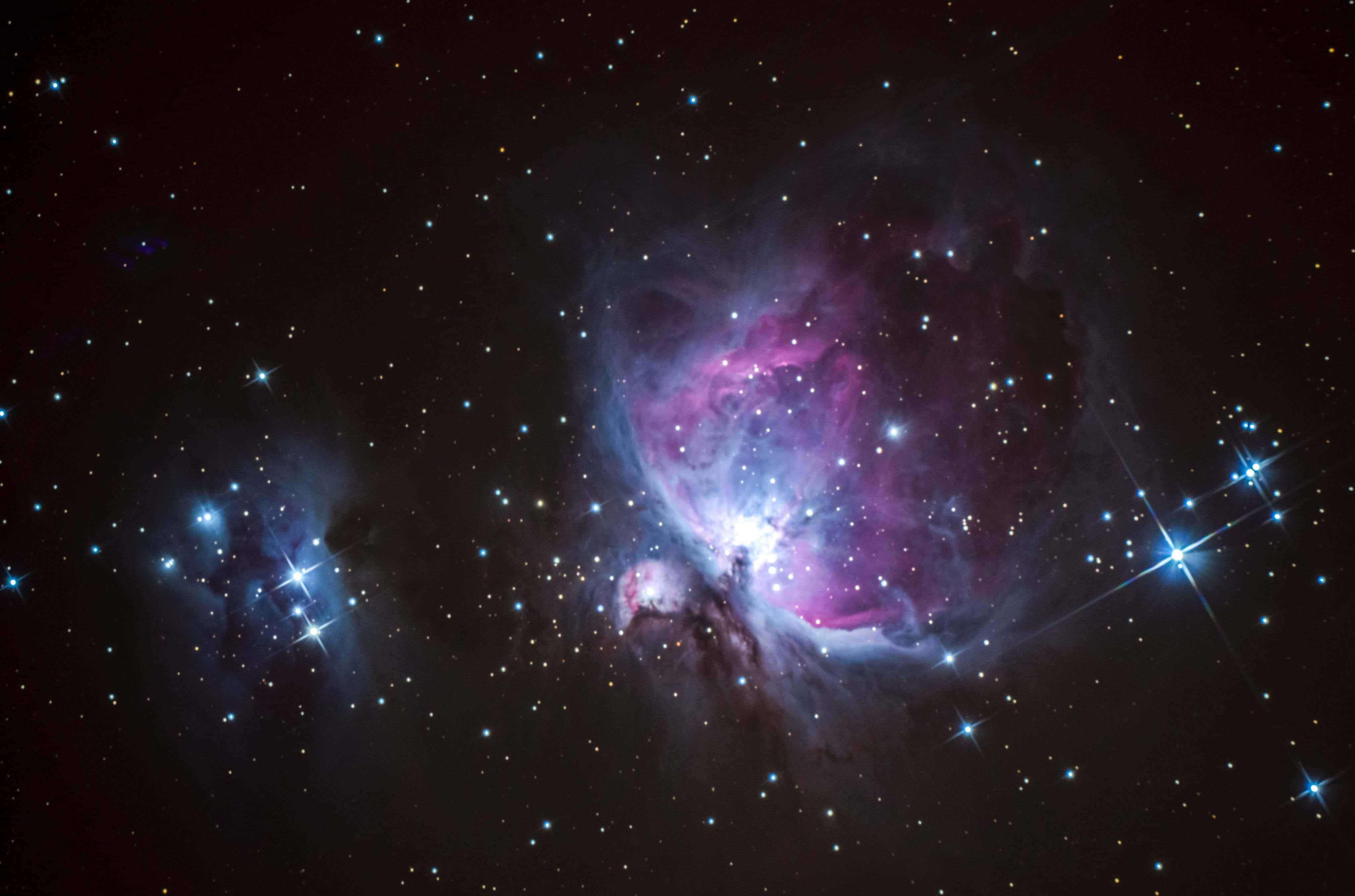 Black And Purple Galaxy 桌布 壁紙 — 一個充滿活力的宇宙星雲在深空的星場中散發出粉紅色和藍色的光芒。