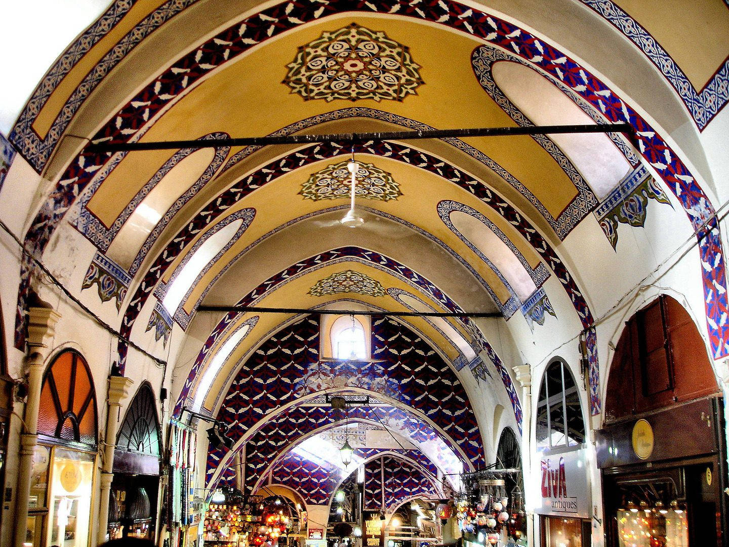 Istanbul 桌布 壁紙 — 一個充滿活力的室內市場，擁有華麗的拱形天花板，飾有複雜的藍色、紅色和金色幾何圖案以及懸掛的燈籠。