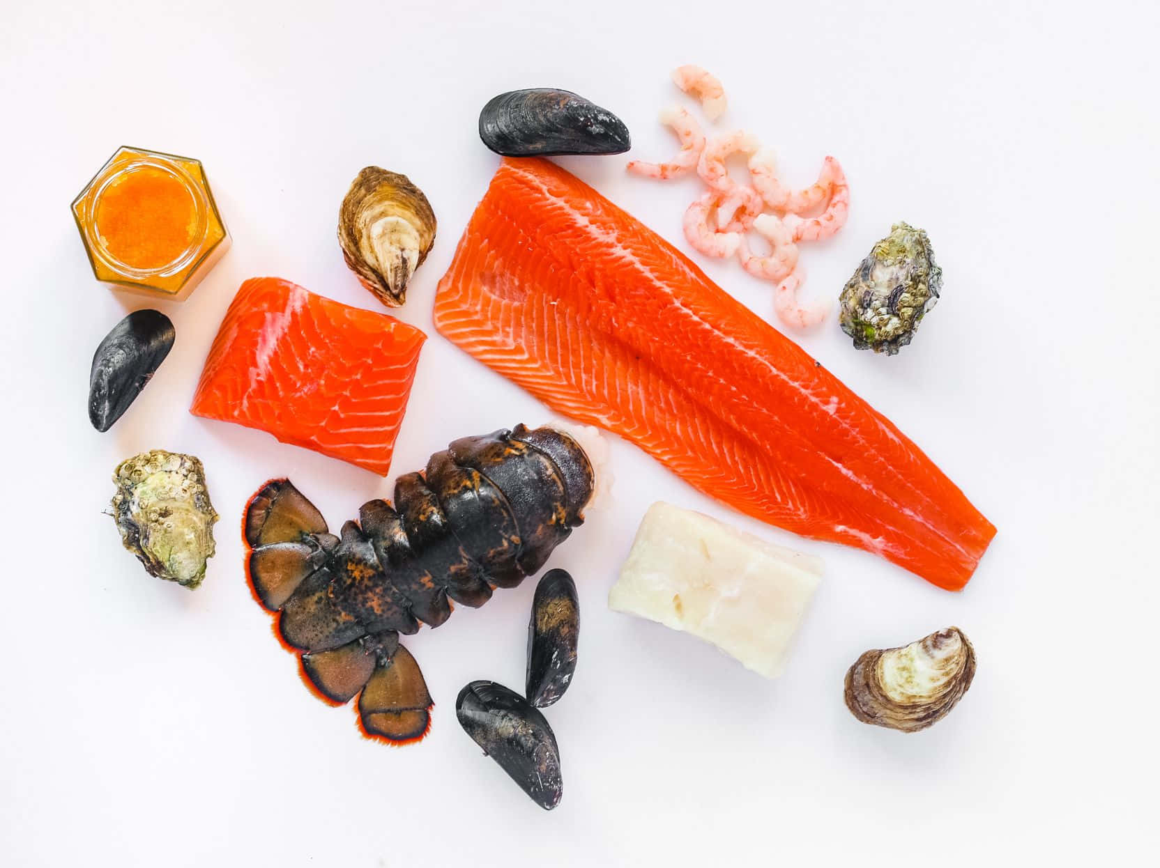 Seafood 桌布 壁紙 — 一個充滿活力的平鋪擺拍，包括鮭魚柳、龍蝦尾、蝦、貽貝和牡蠣，整齊排列在潔白的表面上。