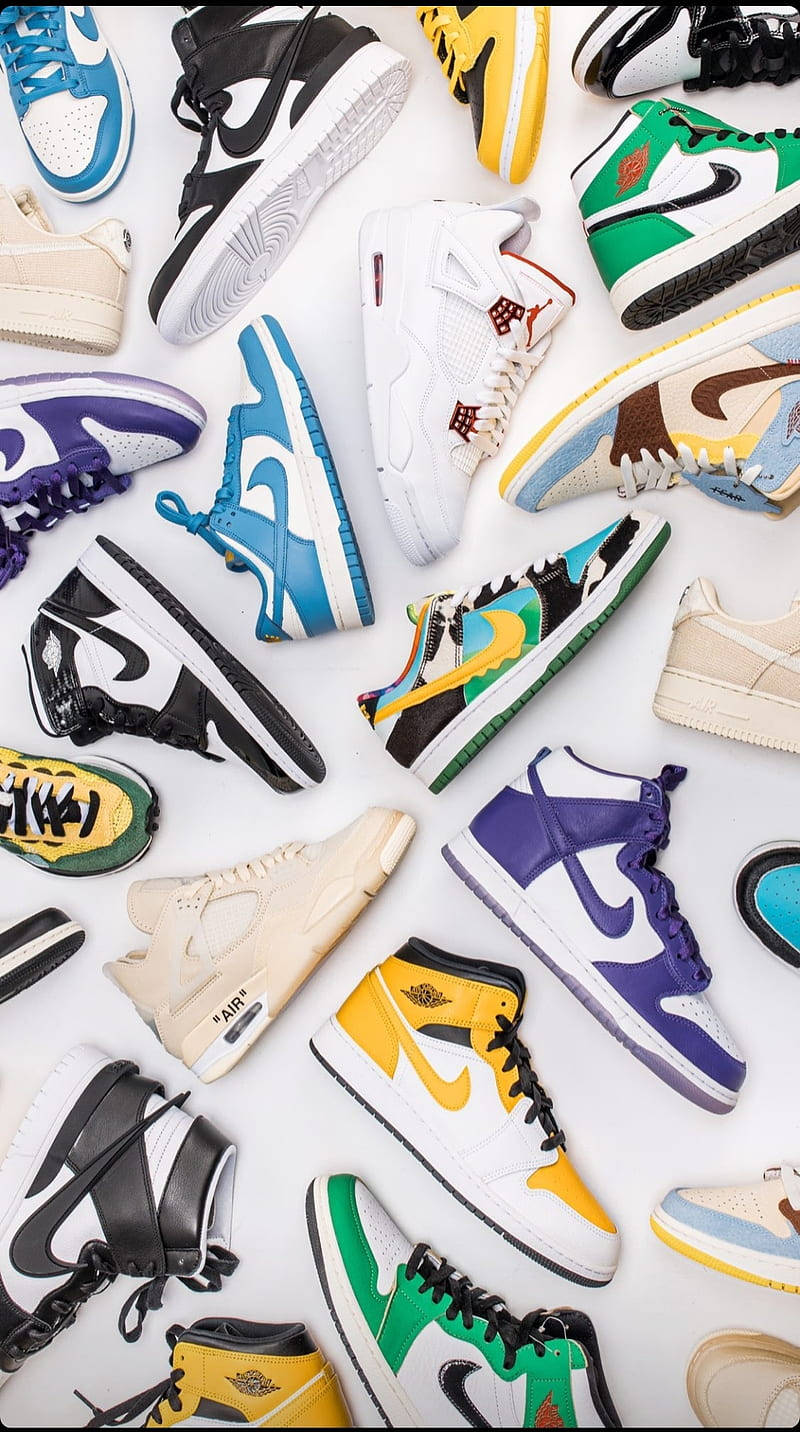 Nike Shoes 桌布 壁紙 — 一個充滿活力的平鋪擺拍，展示各種色彩繽紛的運動鞋，排列在潔白的背景上，展現大膽的設計和多樣的風格。