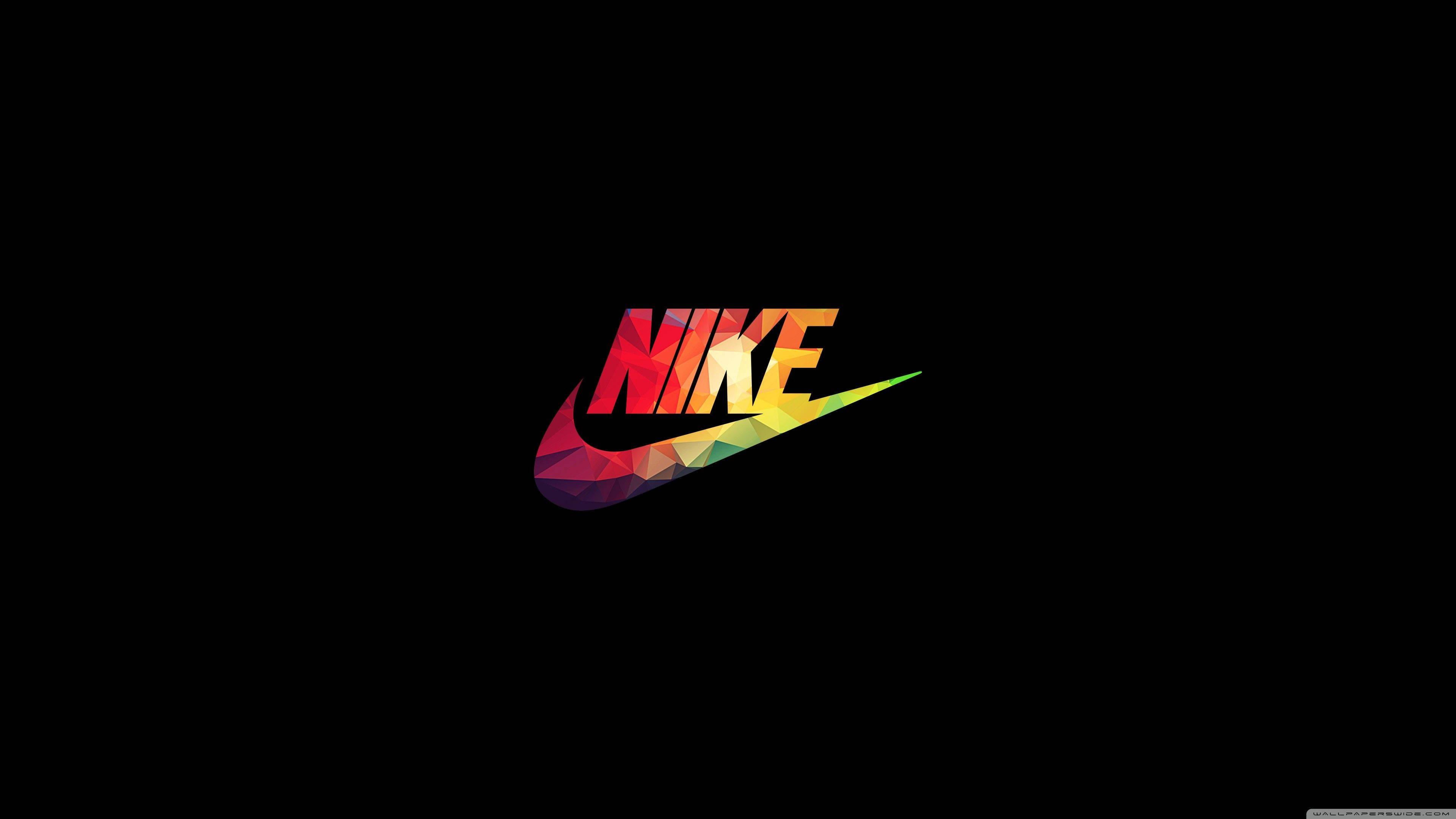 Geometric 桌布 壁紙 — 一個充滿活力的幾何Nike標誌，帶有彩虹多邊形色彩，在純黑色背景上脫穎而出。