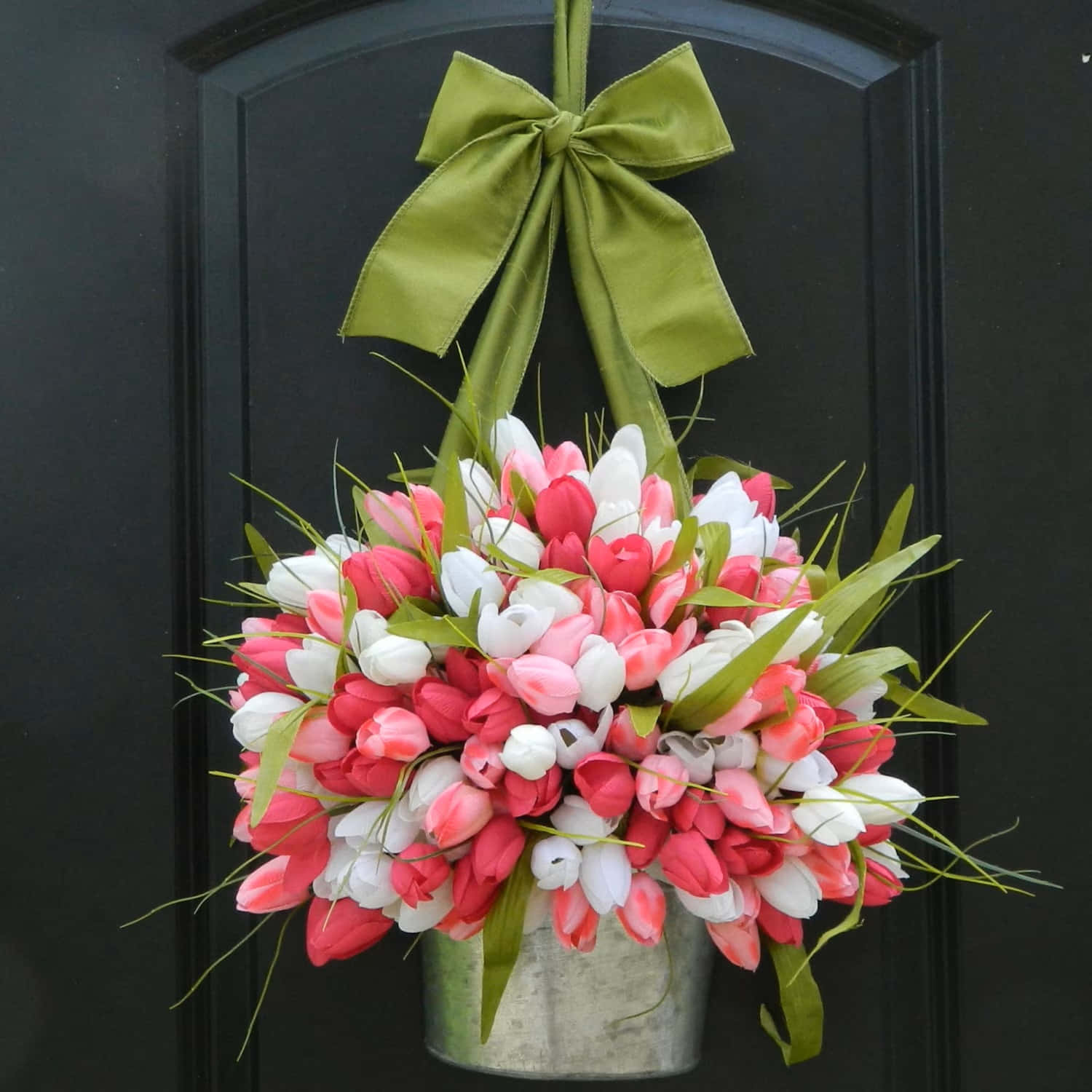Spring Wreaths 桌布 壁紙 — 一個充滿活力的懸掛鬱金香花環，帶有粉白色花朵和綠色絲帶，裝飾著深色的大門。