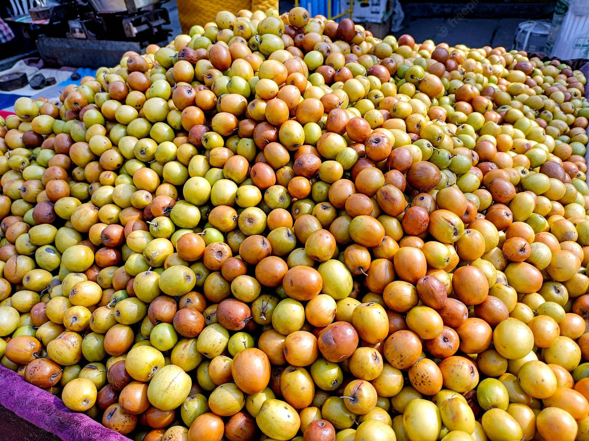 Fruit 桌布 壁紙 — 一個充滿活力的成熟和未成熟紅棗堆，高高堆疊在繁忙的戶外市場攤位上。