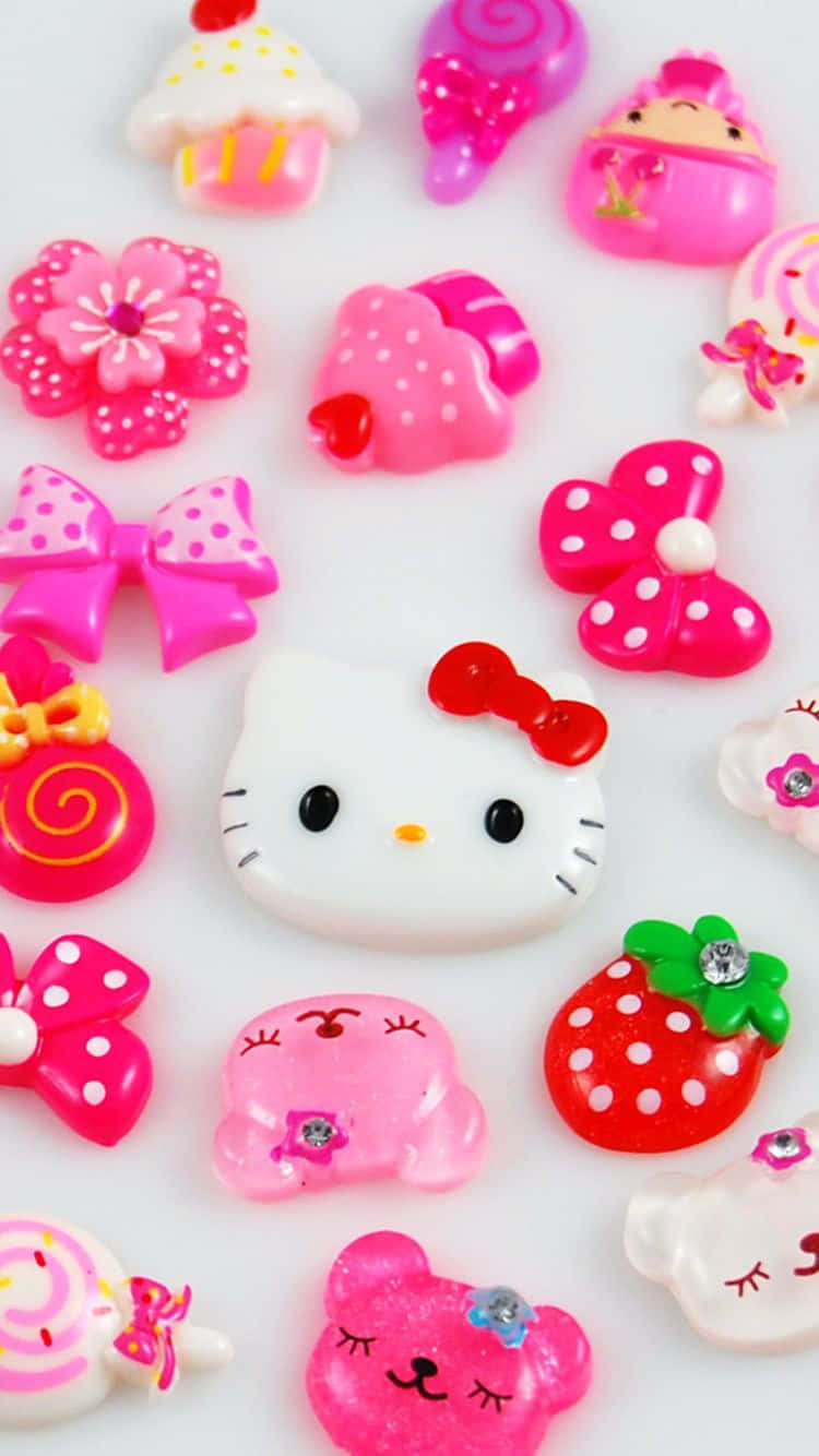 Hello Kitty 桌布 壁紙 — 一個充滿活力的收藏，包括散落在白色表面上的光澤粉紅色Hello Kitty主題飾物和糖果。