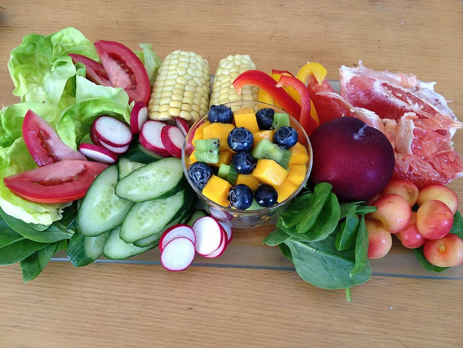 Salad 桌布 壁紙 — 一個充滿活力的新鮮沙拉拼盤，上面擺放著切片蔬菜、水果和玉米，置於木桌上。