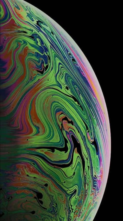 iPhone X Oled 桌布 壁紙 — 一個充滿活力的旋轉肥皂泡，帶有虹彩的綠色、紫色和粉紅色，背景為黑色。