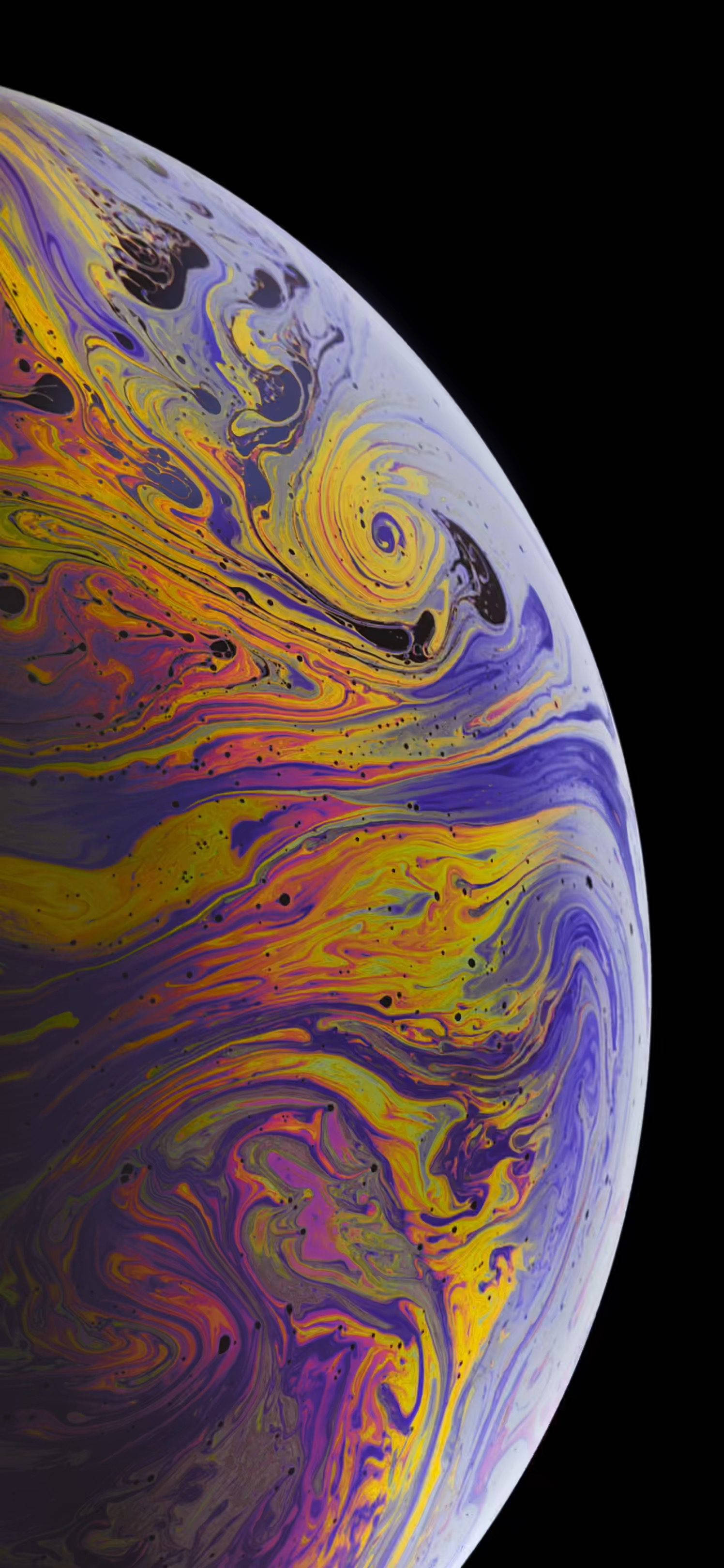 iPhone XS 桌布 壁紙 — 一個充滿活力的旋轉肥皂泡，帶有虹彩黃色、紫色和粉紅色，在純黑色背景上。