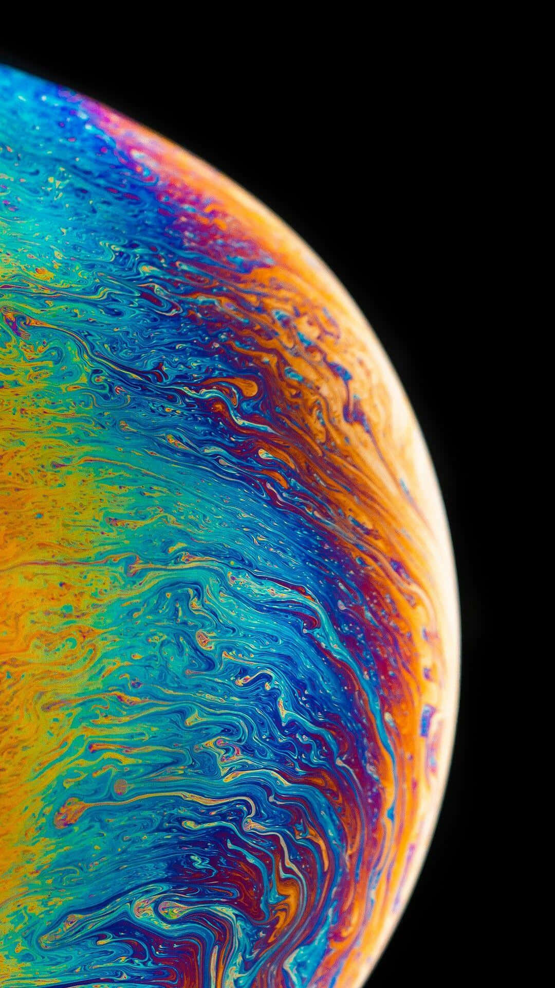 iPhone X 桌布 壁紙 — 一個充滿活力的旋轉肥皂泡，帶有虹彩藍、橙和黃色，襯托在 stark 黑色背景上。