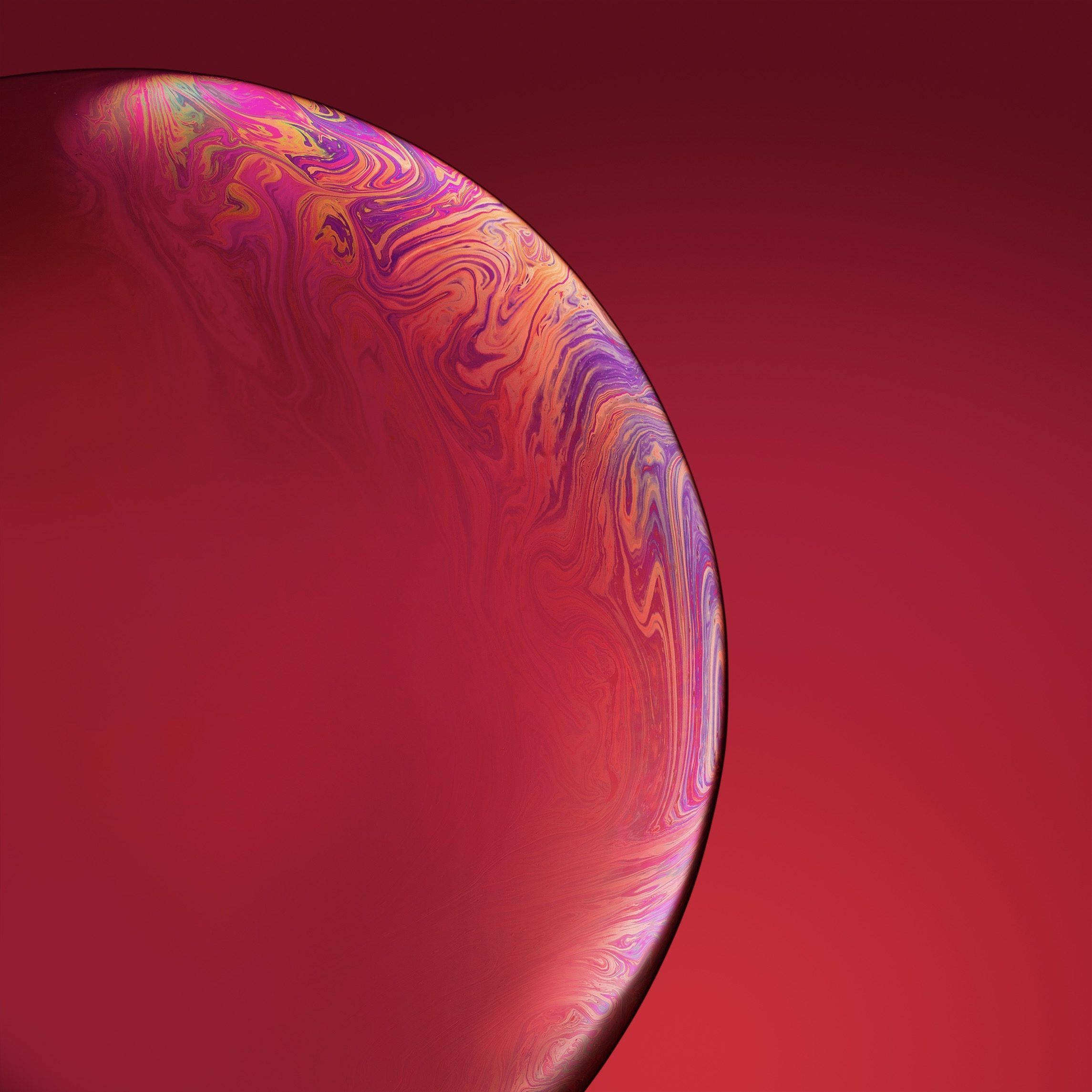 iPhone XR 桌布 壁紙 — 一個充滿活力的旋轉肥皂泡，帶有虹彩粉紅色、紫色和橙色色調，漂浮在深紅色漸變背景上。
